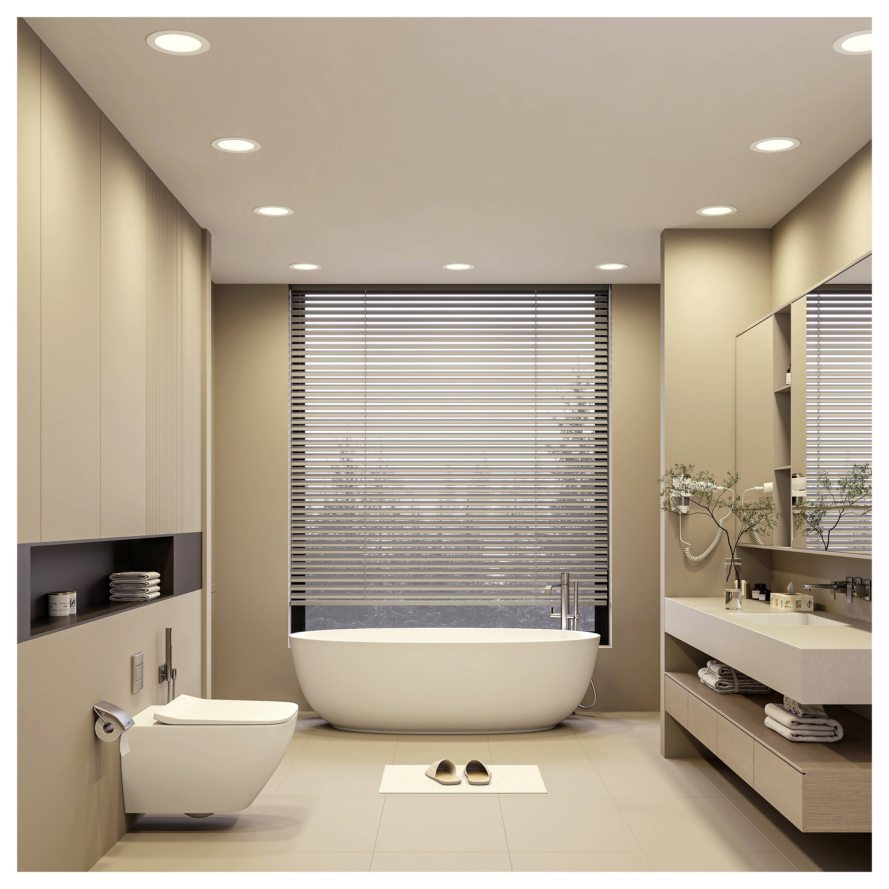 Modernes beiges Badezimmer mit einer freistehenden Badewanne am Fenster, wandmontierter Toilette, Waschtisch und Badvorleger mit Hausschuhen.