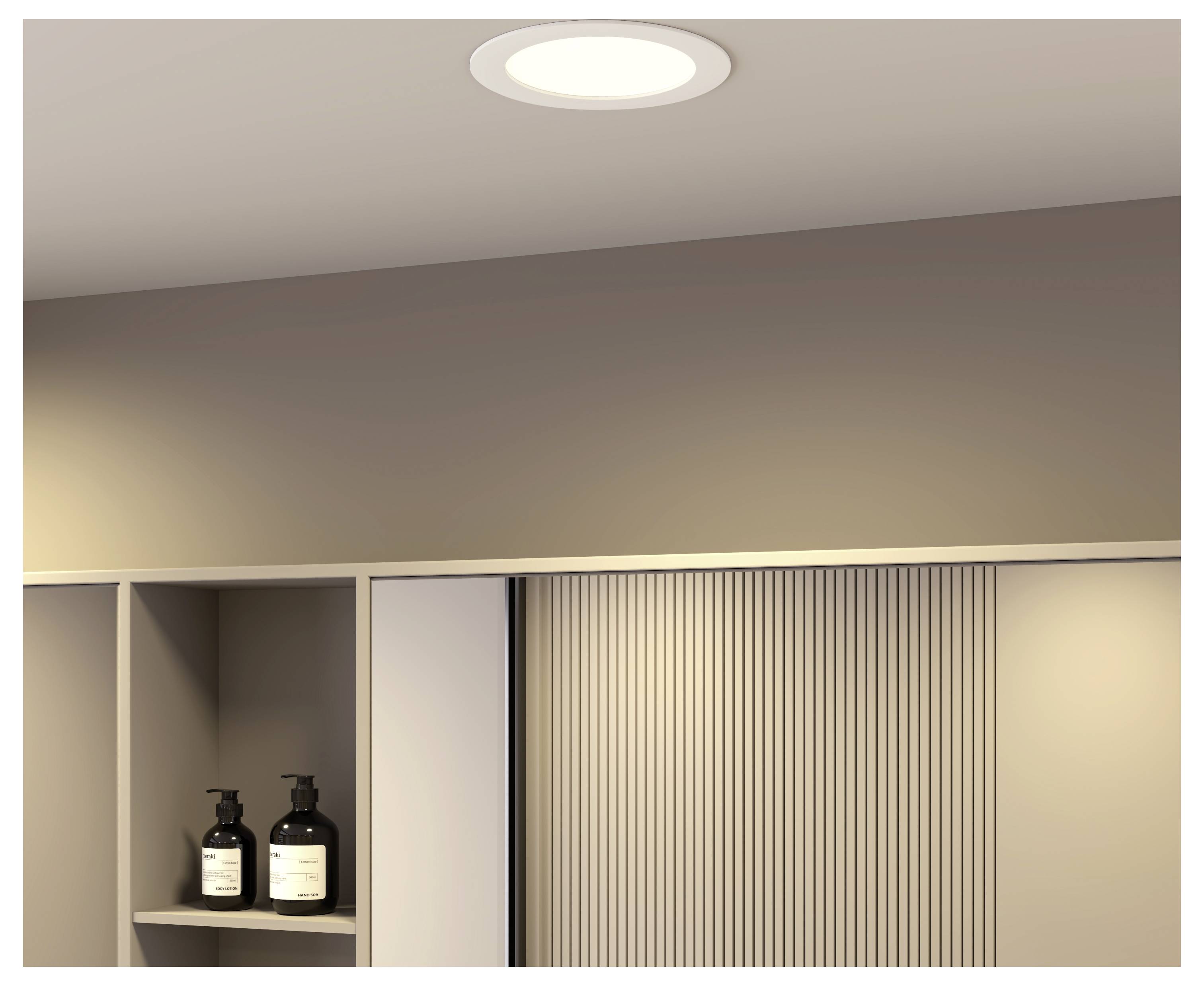 Moderne beige Wand mit einer eingelassenen Ablage, die zwei dunkle Seifenspender hält, und einem vertikalen Lamellenpaneel, wahrscheinlich ein Badezimmer- oder Spa-Interieur.