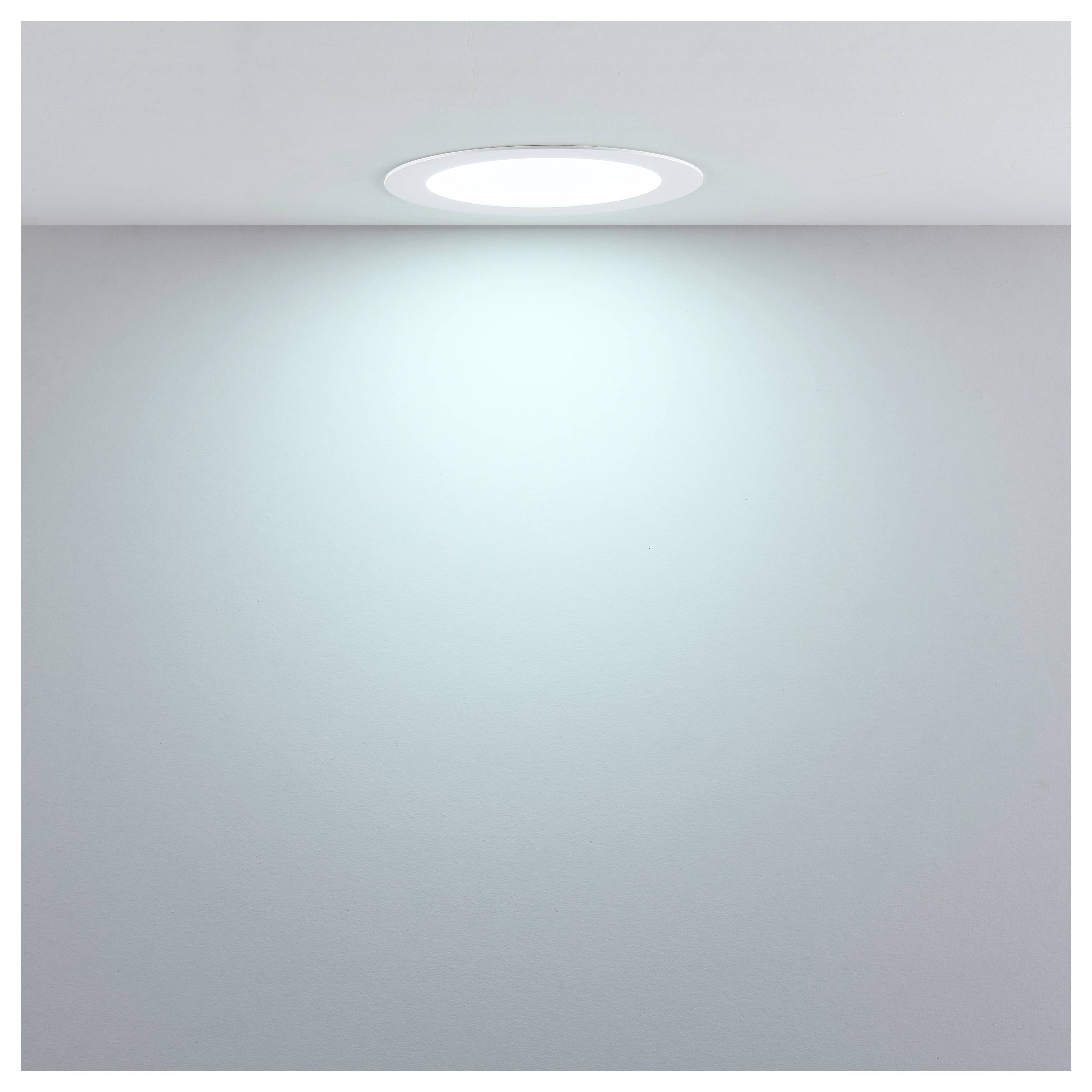 In der Decke eingelassenes rundes Deckenleuchte, die auf einer einfachen Wand und Decke ein weiches blauweißes Glühen wirft.
