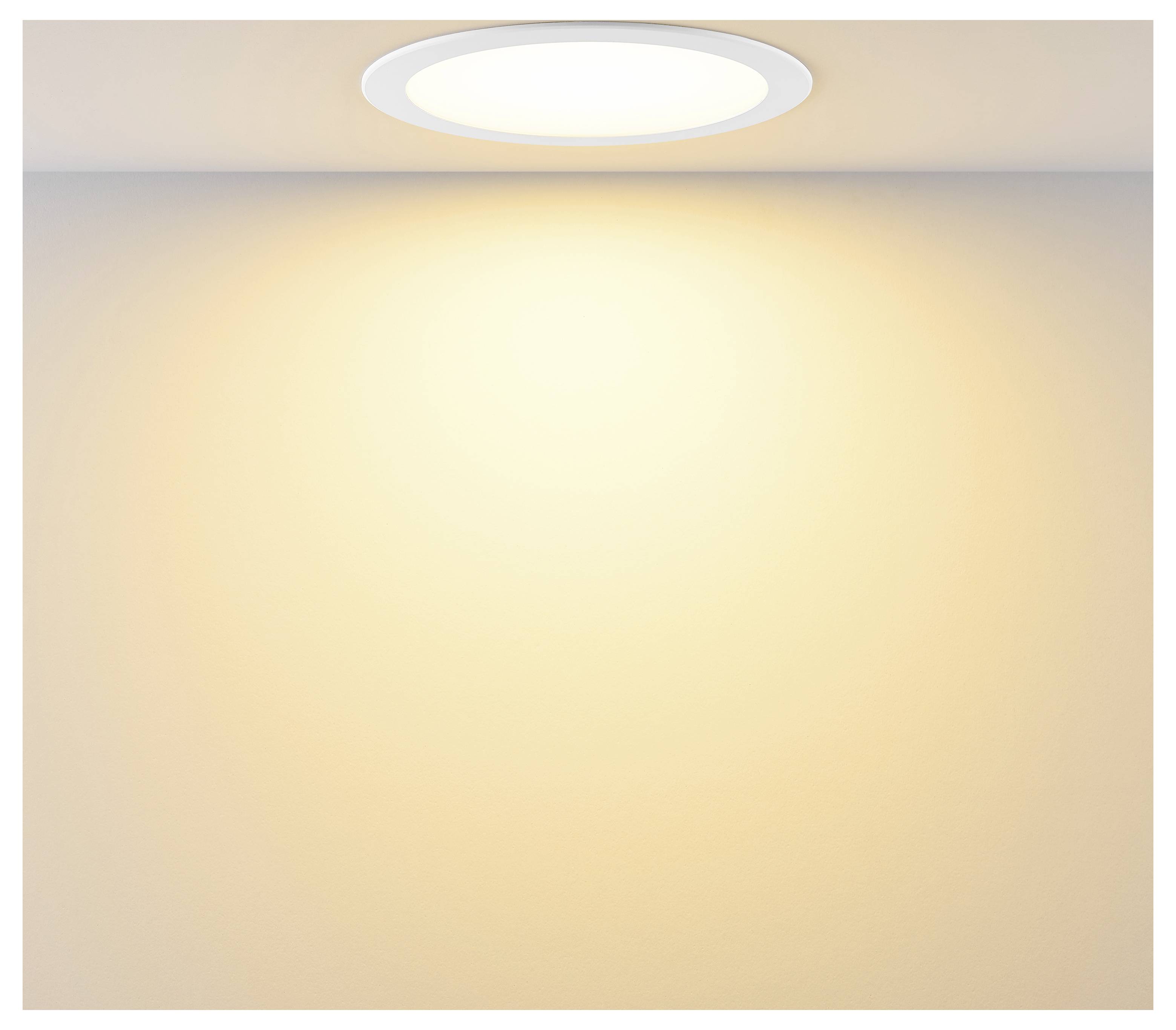 An der Decke angebrachte eingelassene Leuchte, die einen warmen Glanz auf eine leere beige Wand wirft.