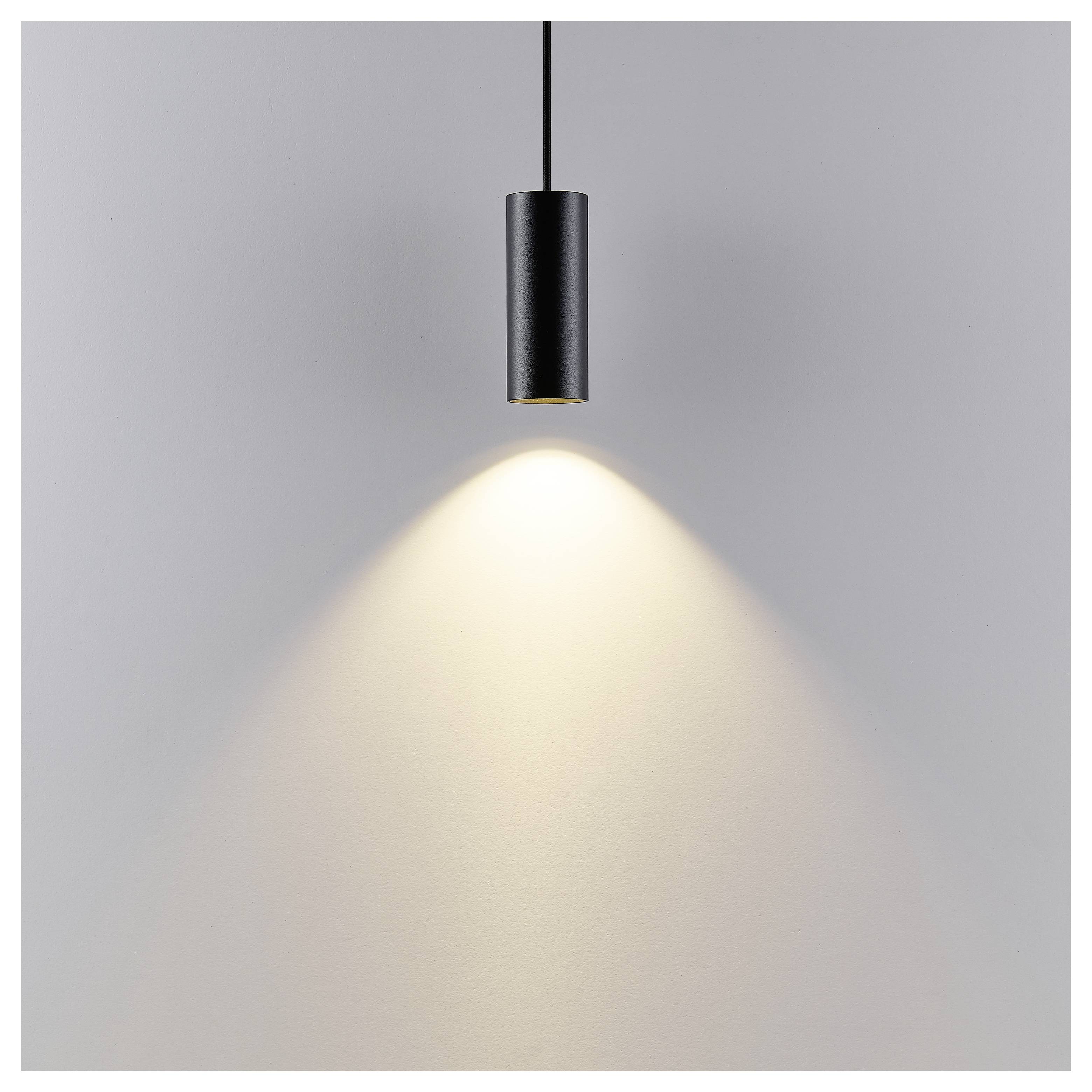 Schwarze Pendelleuchte, die einen warmen Lichtkegel auf eine schlichte graue Wand wirft.