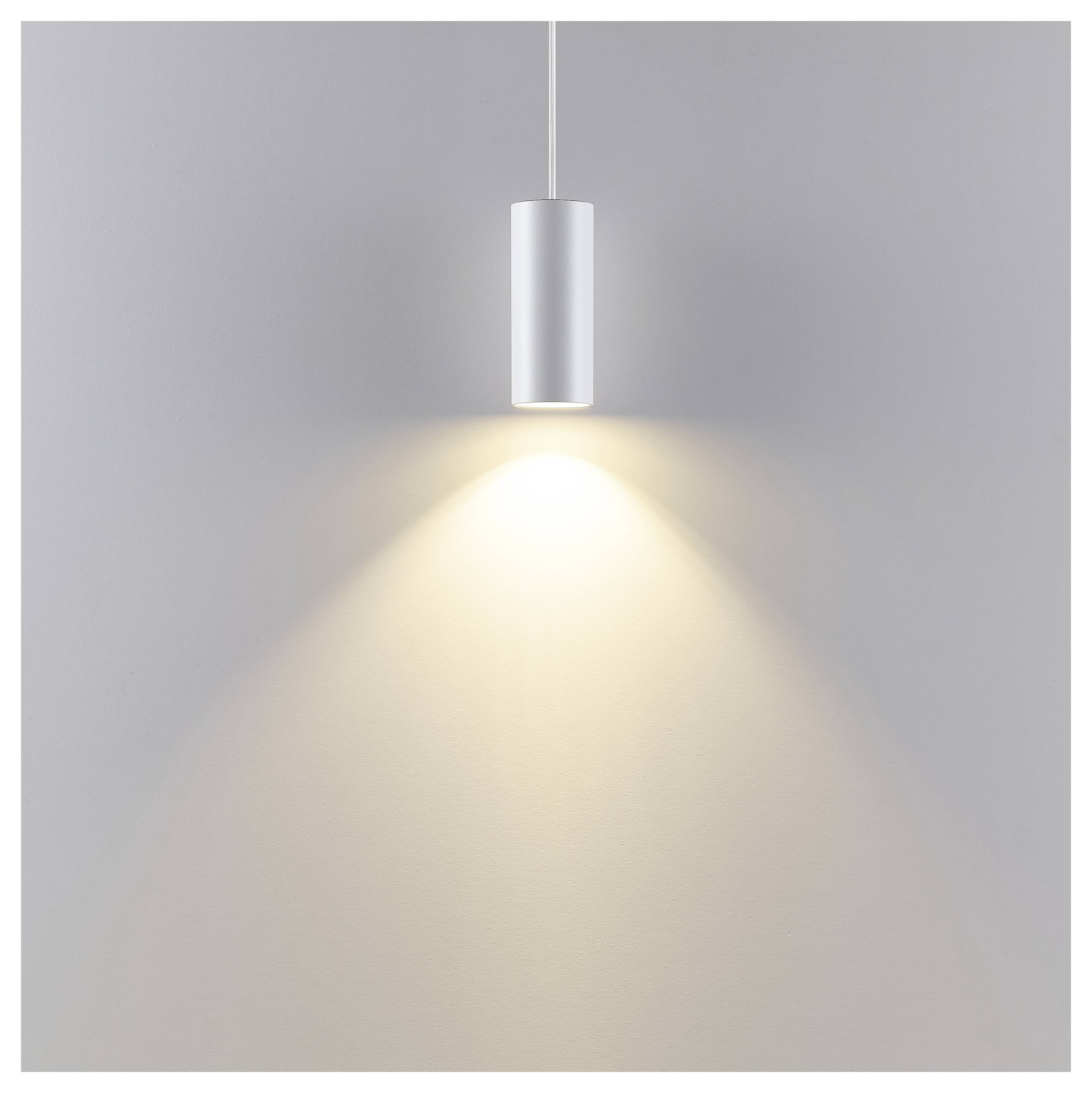 Minimalistische Silberhängeleuchte, die einen warmen Lichtkegel auf eine schlichte graue Wand wirft.