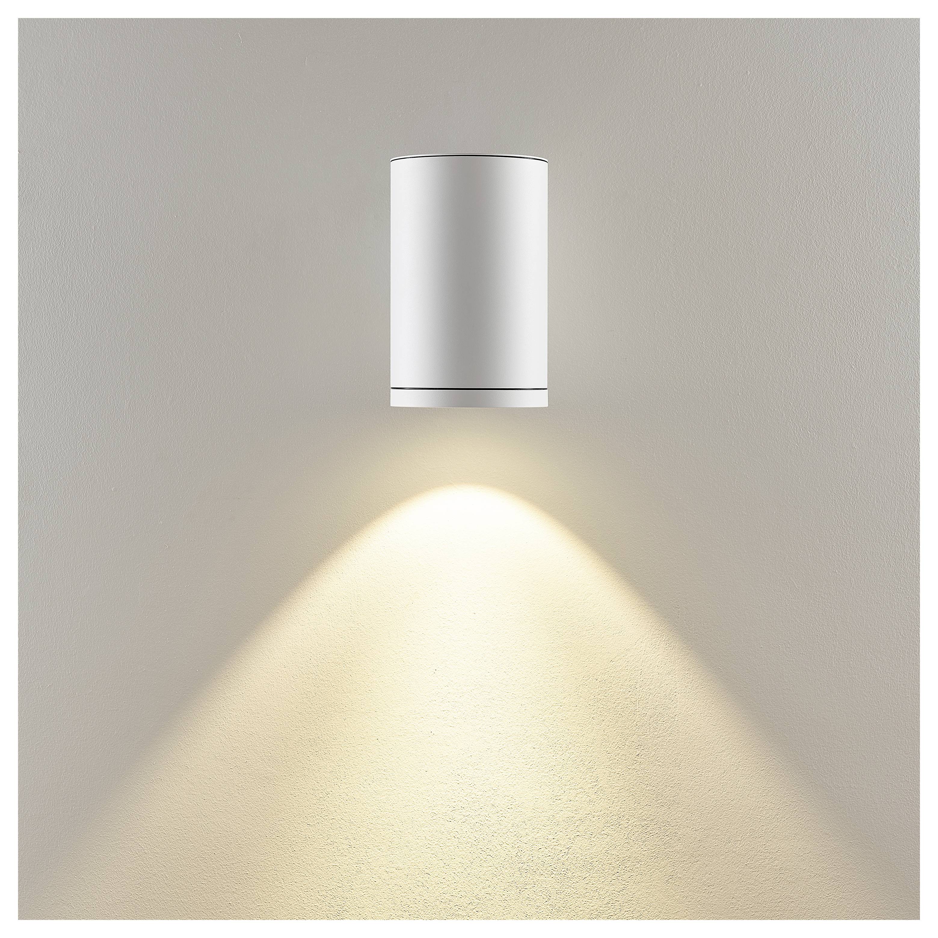 Eine moderne Wandleuchte wirft ein warmes, kegelförmiges Licht auf eine neutrale Wand herab.