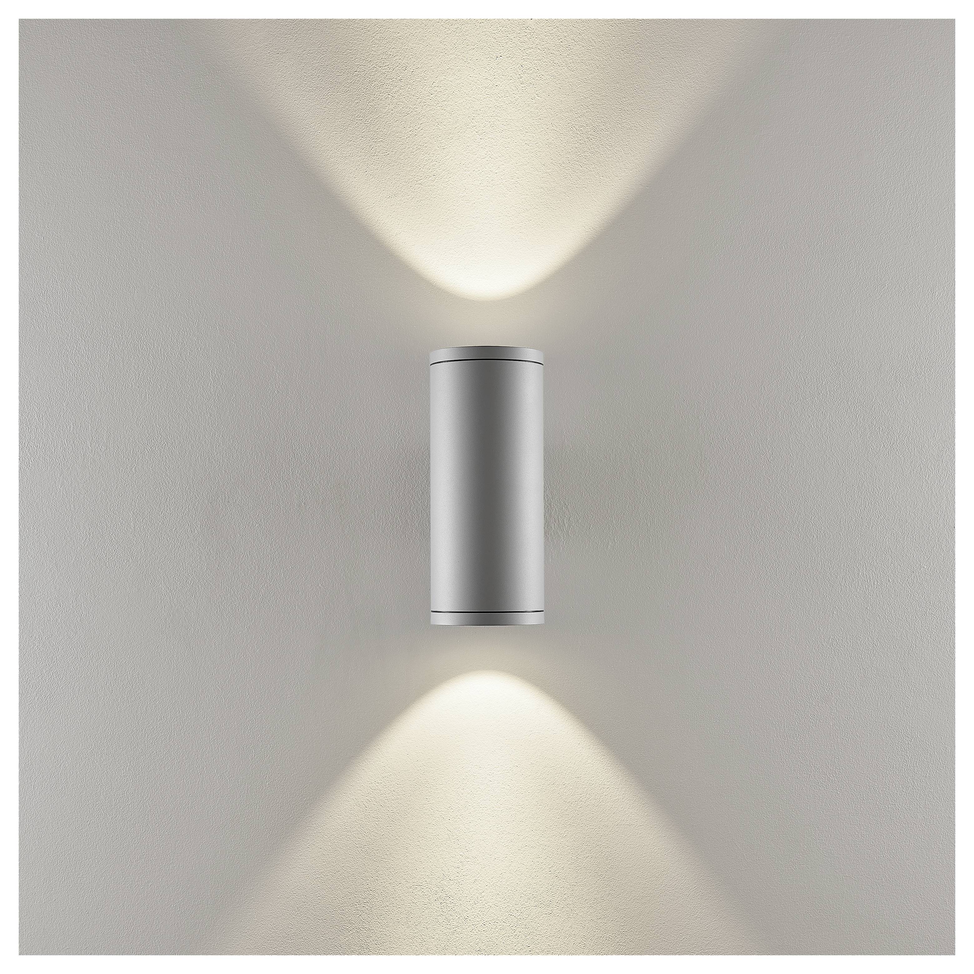 Minimale zylindrische Wandleuchte, die weiches Licht nach oben und unten auf eine beige Wand wirft