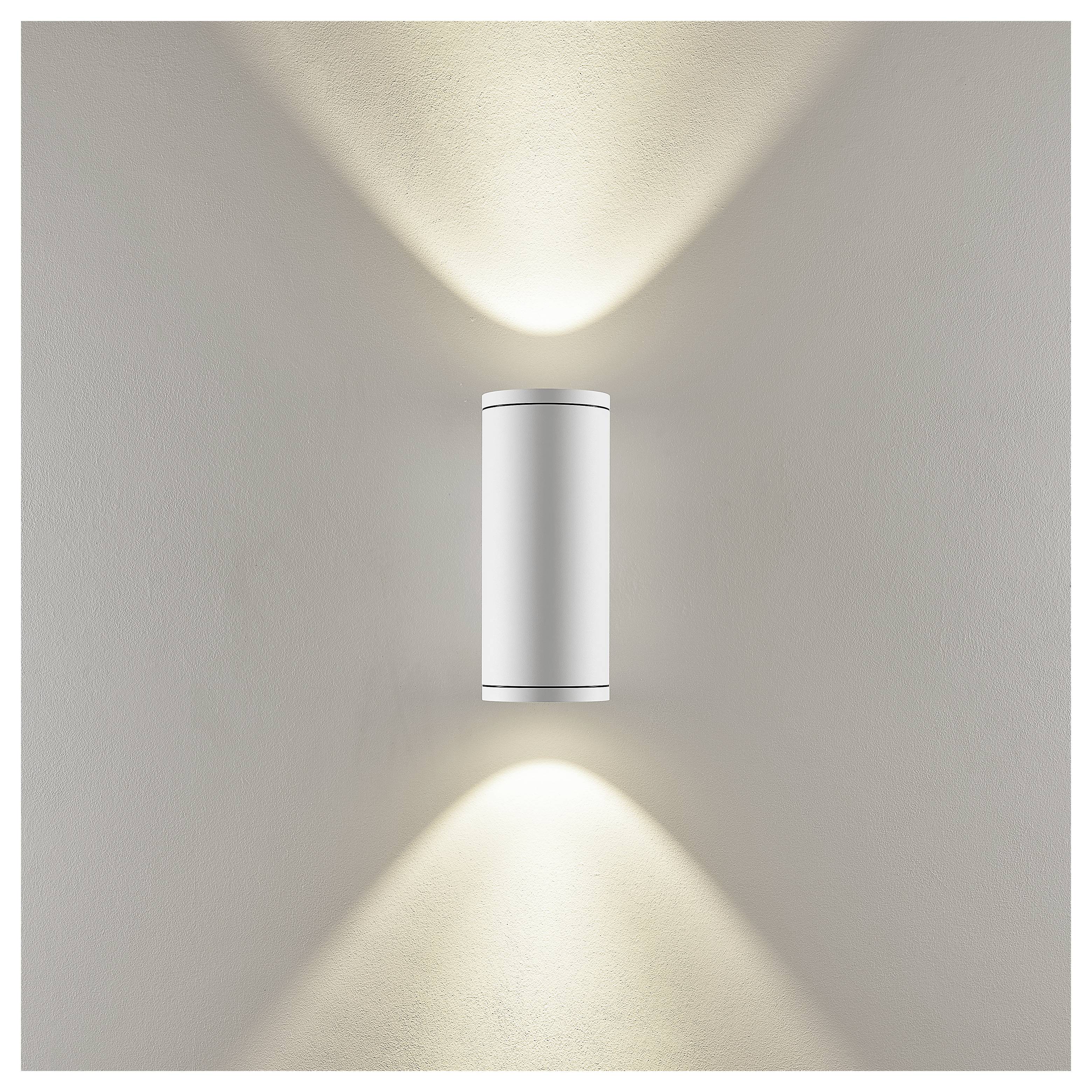 Moderne zylindrische Wandleuchte wirft warme Lichtstrahlen nach oben und unten auf eine schlichte Wand.