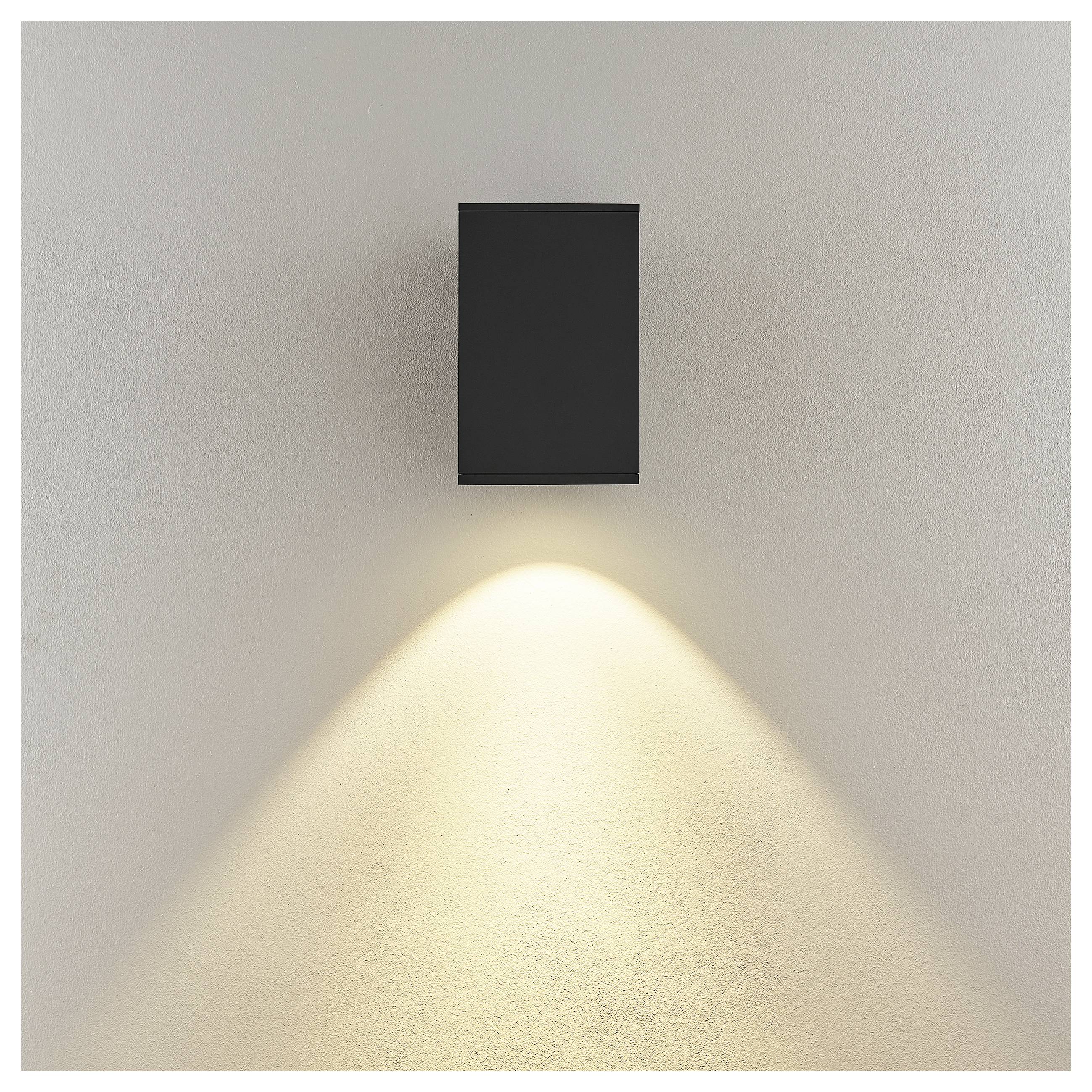 Schwarze rechteckige Wandleuchte, die einen warmen, nach unten gerichteten Lichtkegel auf eine beige Wand wirft