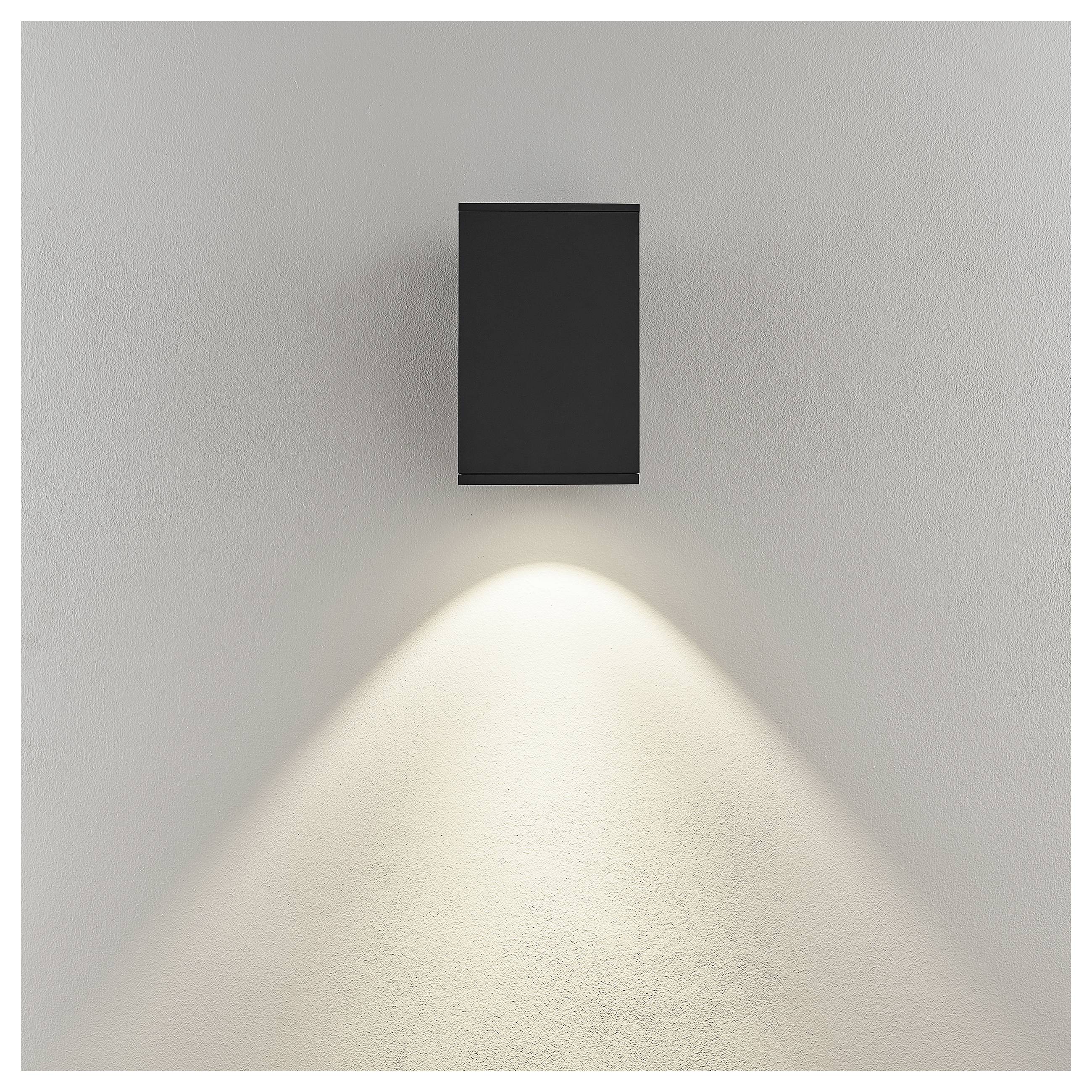 Schwarze, an der Wand montierte Leuchte, die einen warmen, nach unten gerichteten Lichtkegel auf eine hellfarbige Wand wirft.