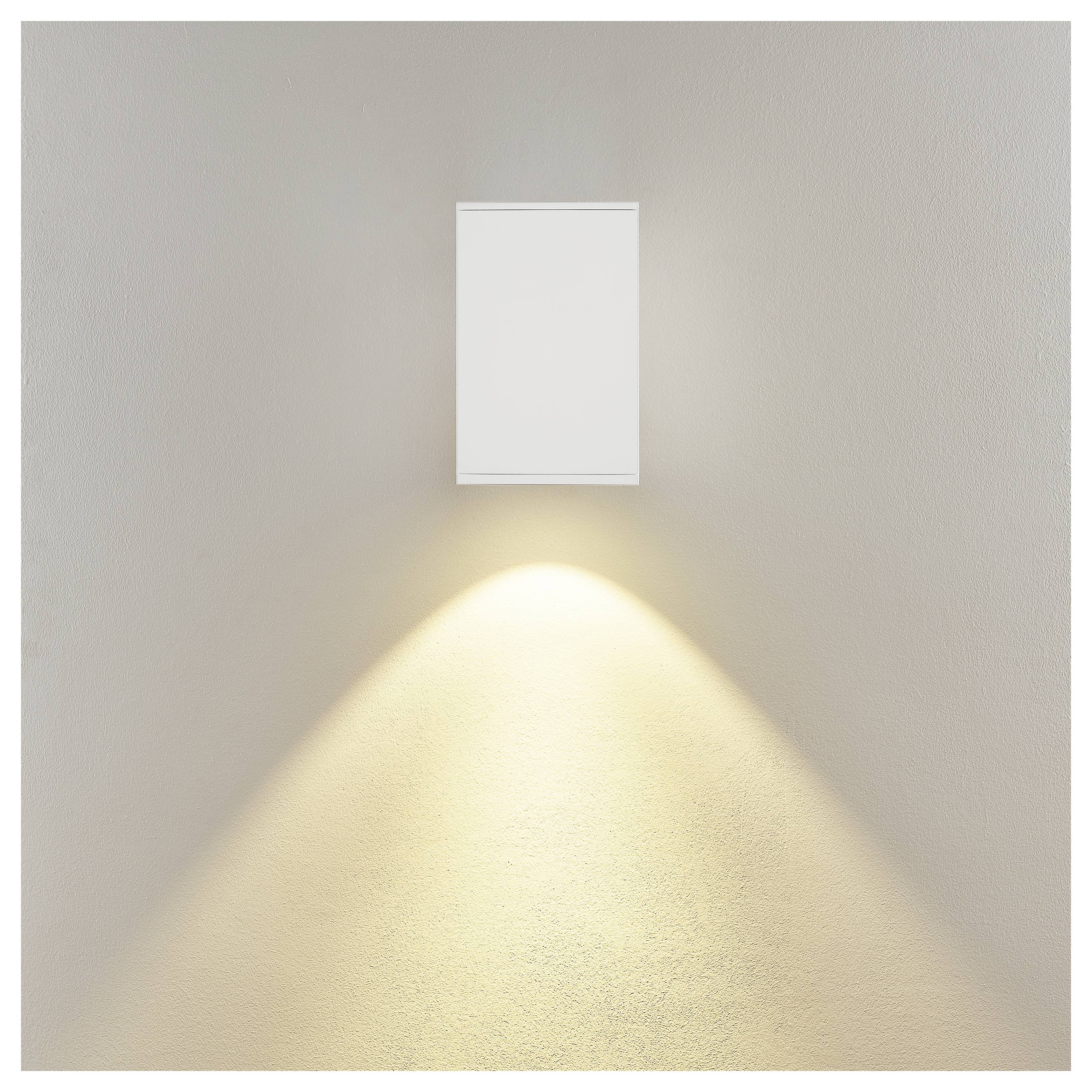 An der Wand montierte rechteckige Leuchte, die einen warmen, nach unten gerichteten Lichtkegel auf eine schlichte beige Wand wirft.