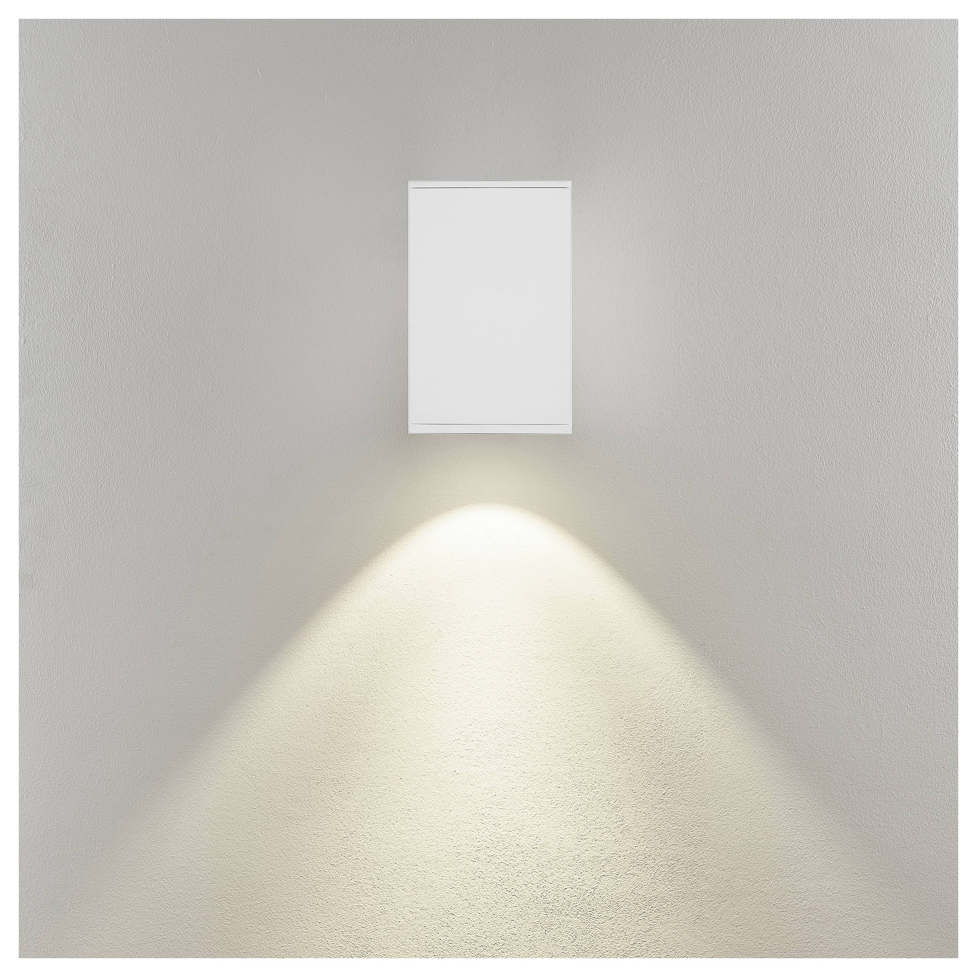 An der Wand montierte rechteckige Leuchte, die einen warmen Lichtkegel nach unten auf eine schlichte beigefarbene Wand wirft.
