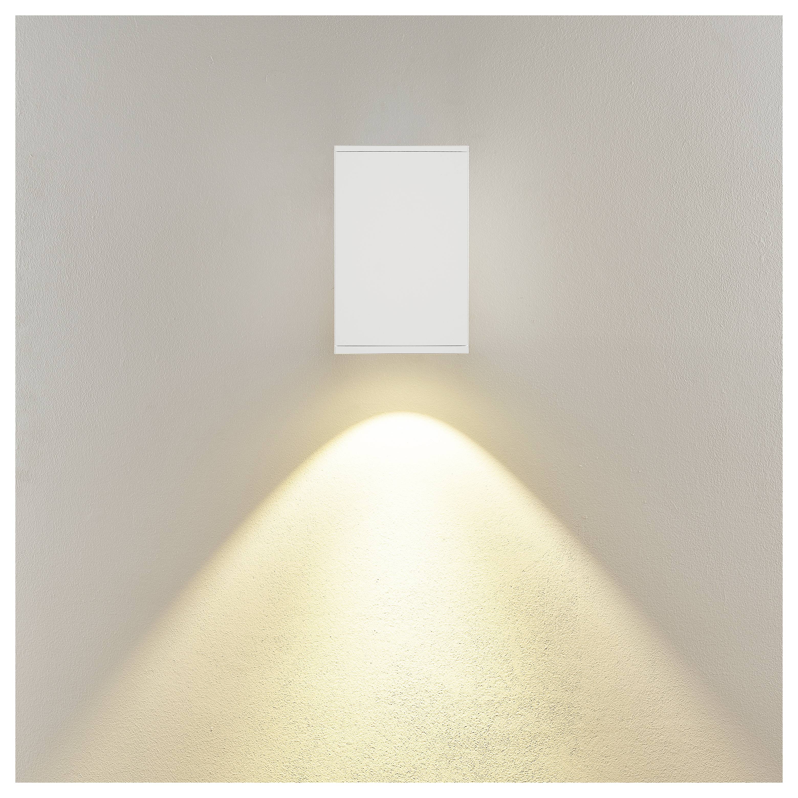 Minimalistische Wandleuchte mit einem rechteckigen weißen Leuchtenkörper, der einen warmen dreieckigen Lichtstrahl nach unten auf eine beige Wand wirft.