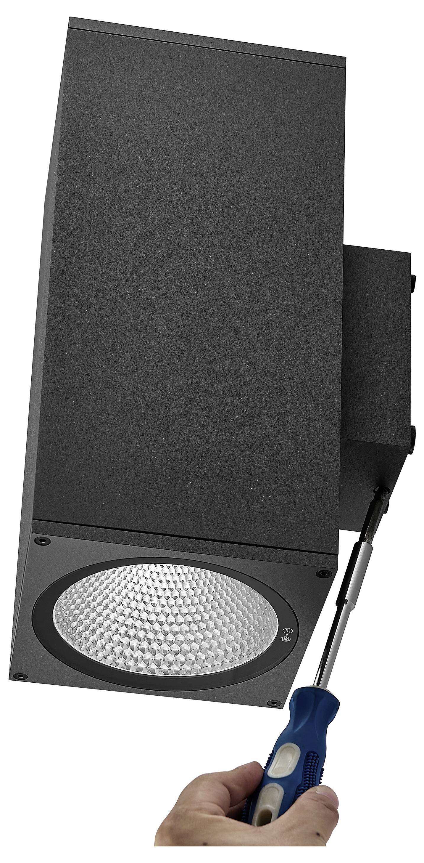 Hand mit einem Schraubenzieher zum Einstellen einer schwarzen rechteckigen Außenleuchte mit einer runden LED-Linse.