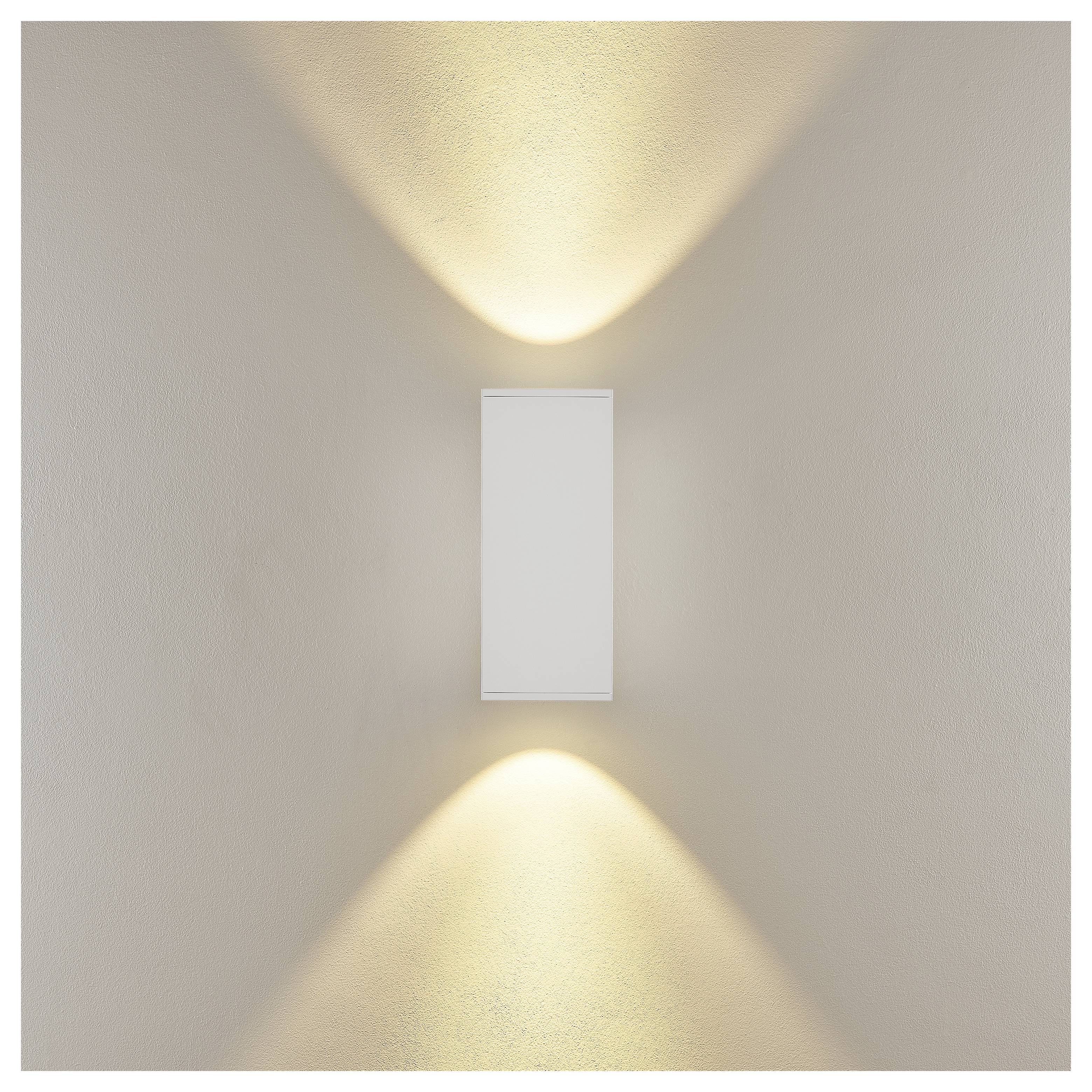 Wandmontierte rechteckige Leuchte, die warme Lichtstrahlen nach oben und unten auf eine beige Wand wirft.