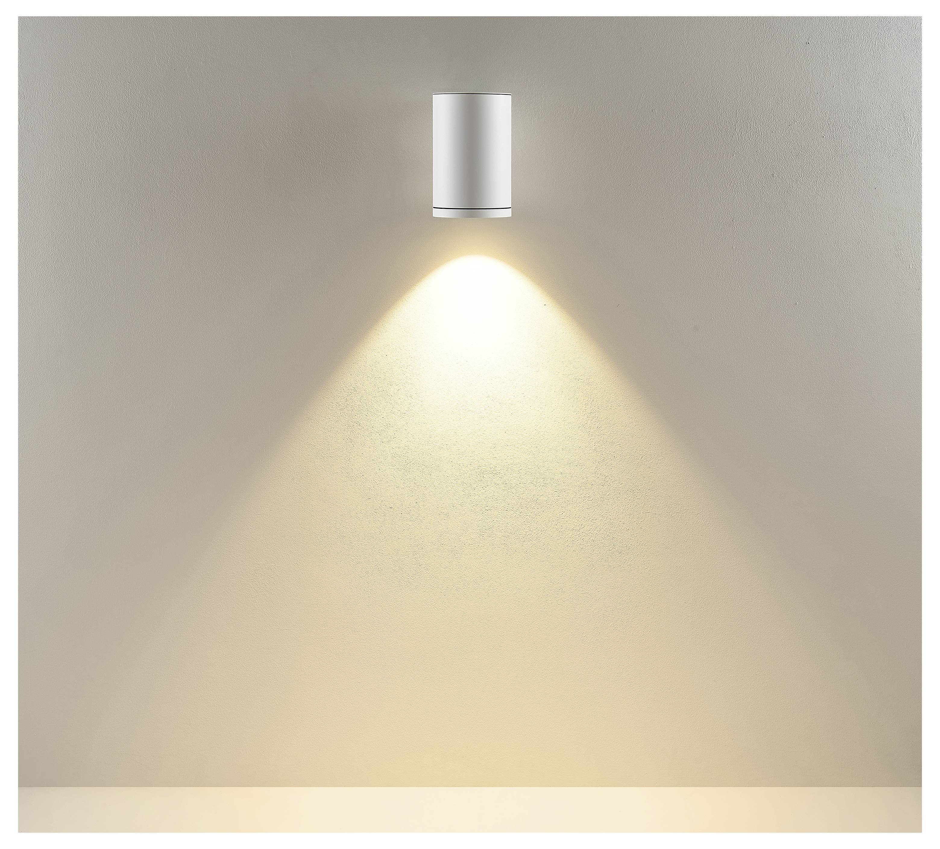 Moderne zylindrische Wandleuchte, die einen warmen, nach unten gerichteten Lichtkegel auf eine schlichte beige Wand wirft.