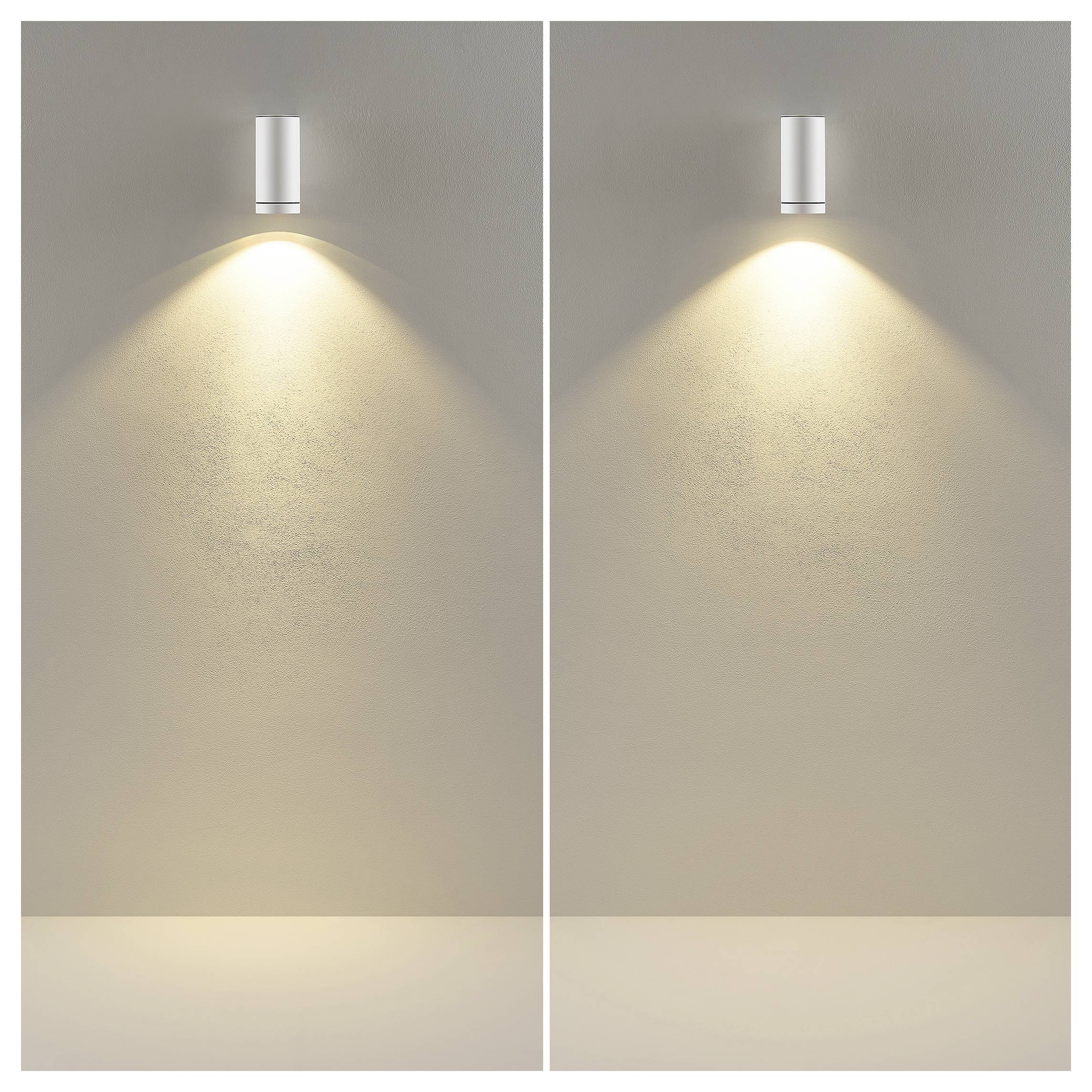 Zwei nebeneinander angebrachte Wandleuchten werfen warme, nach unten gerichtete Lichtstrahlen auf eine beige Wand und erzeugen dabei einen symmetrischen Beleuchtungseffekt.