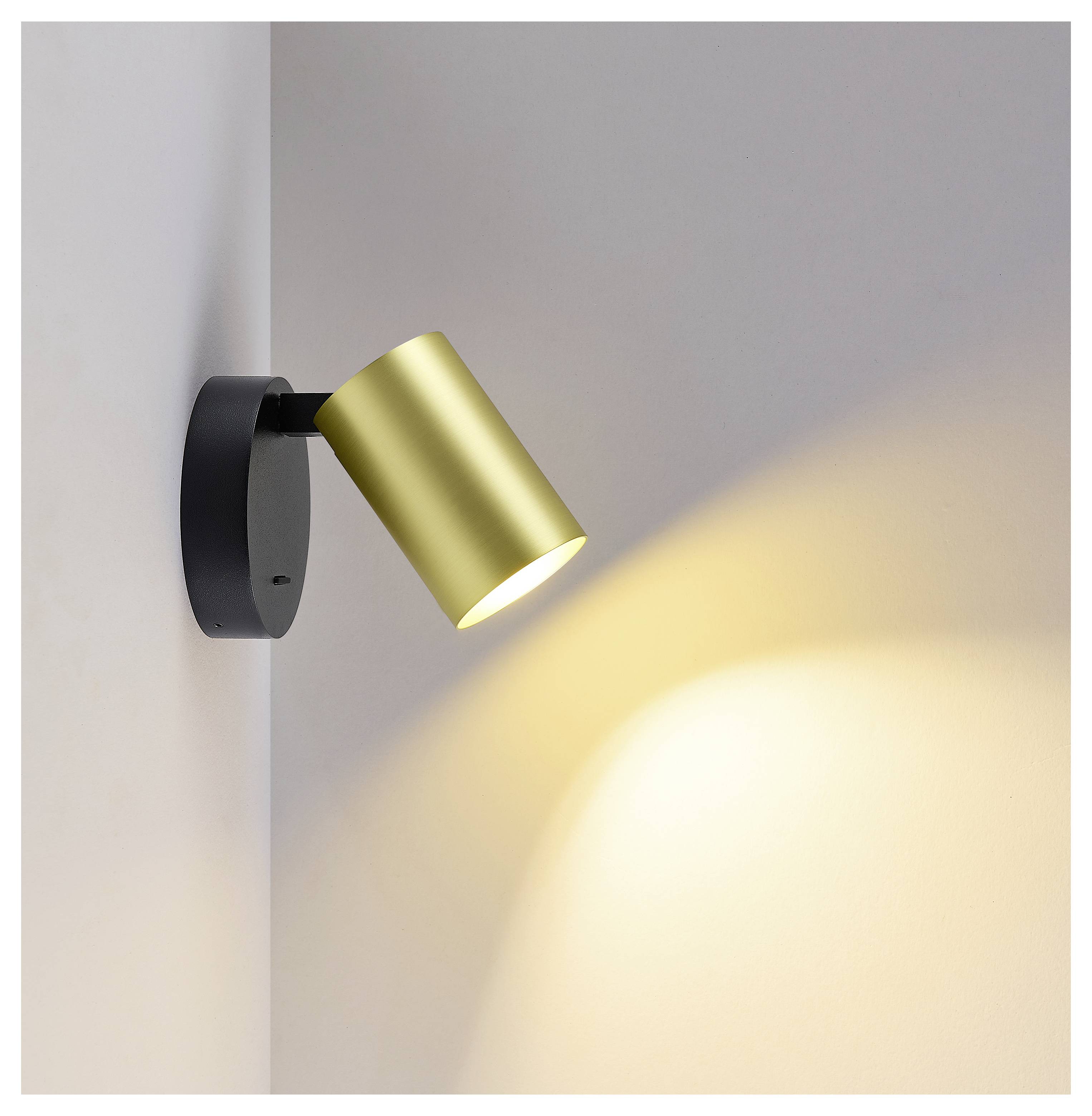 Moderner wandmontierter Strahler mit goldenem zylindrischem Schirm, der einen warmen Lichtstrahl auf eine Eckwand wirft.