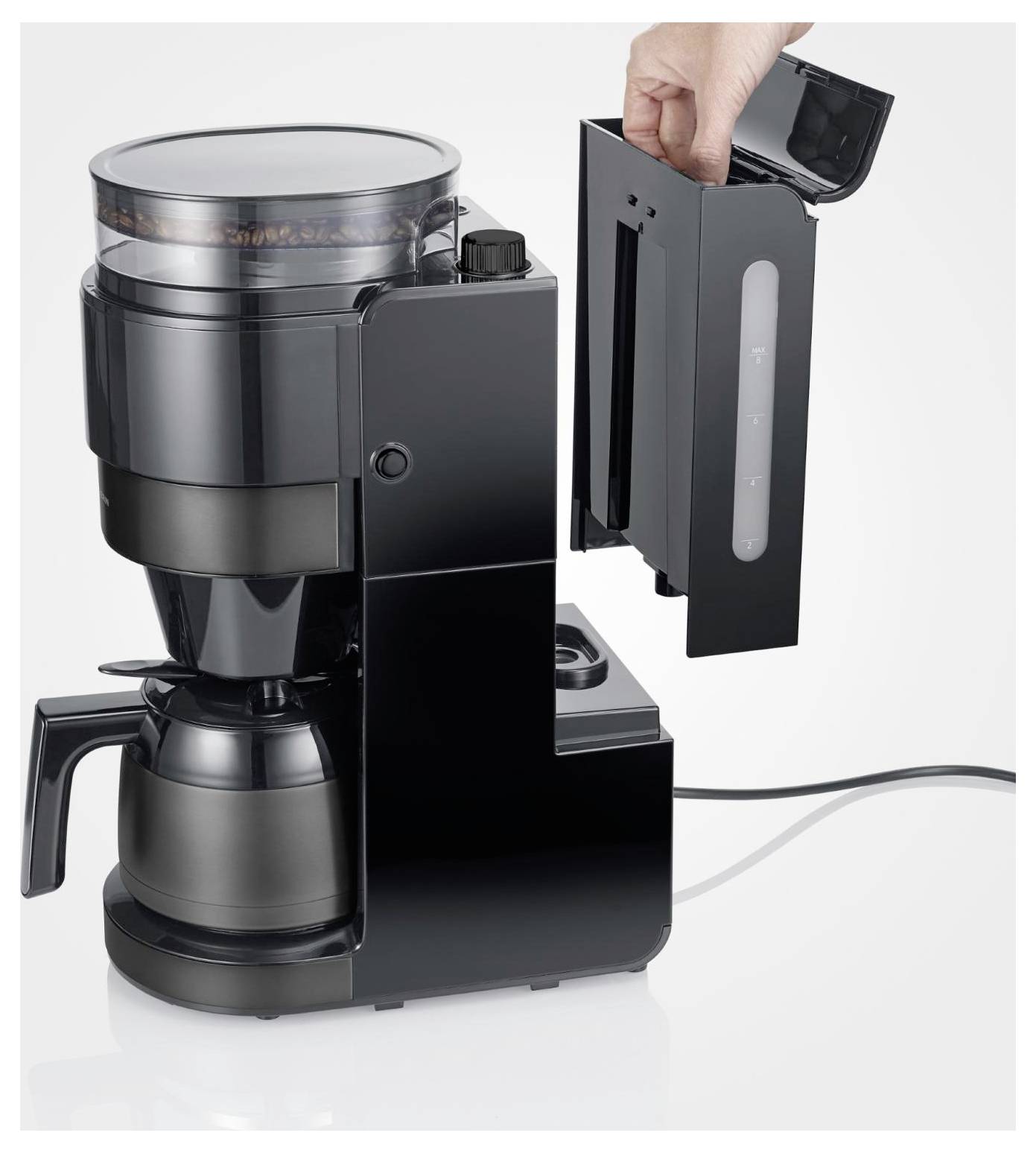 Schwarze Kaffeemaschine mit Glaskanne; Hand führt einen Wasserbehälter in das Seitenkompartiment ein.