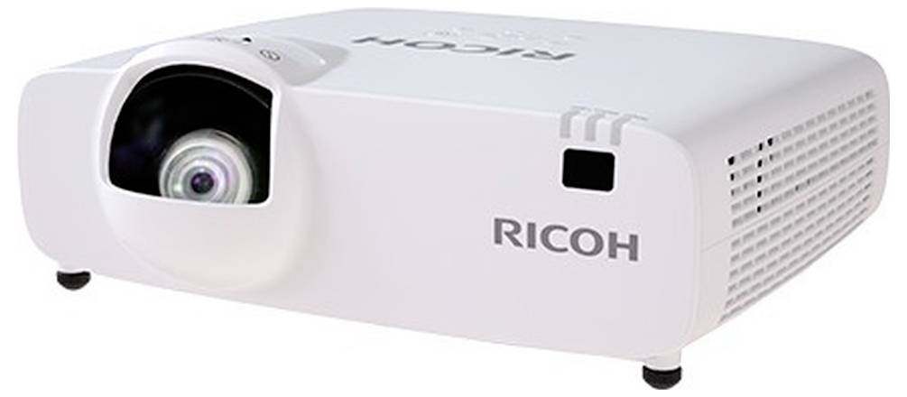 Weißer Ricoh-Projektor von vorne links gezeigt, mit sichtbarem Objektiv, Lüftungsgittern und Logo.