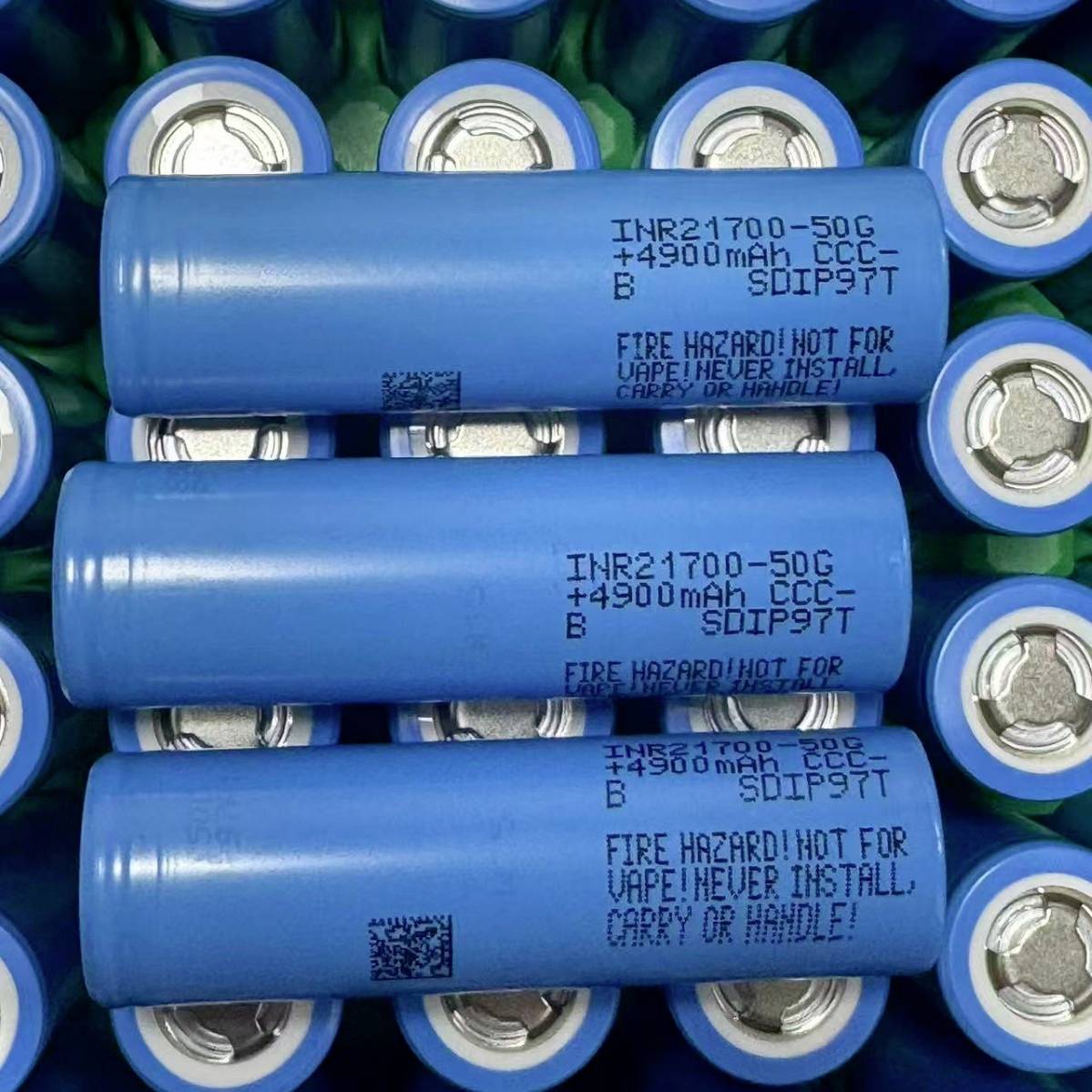 Drei blaue zylindrische Lithium-Ionen-Batterien, die in einem Tablett gestapelt sind, mit der Bezeichnung „INR21700-50G 4900mAh