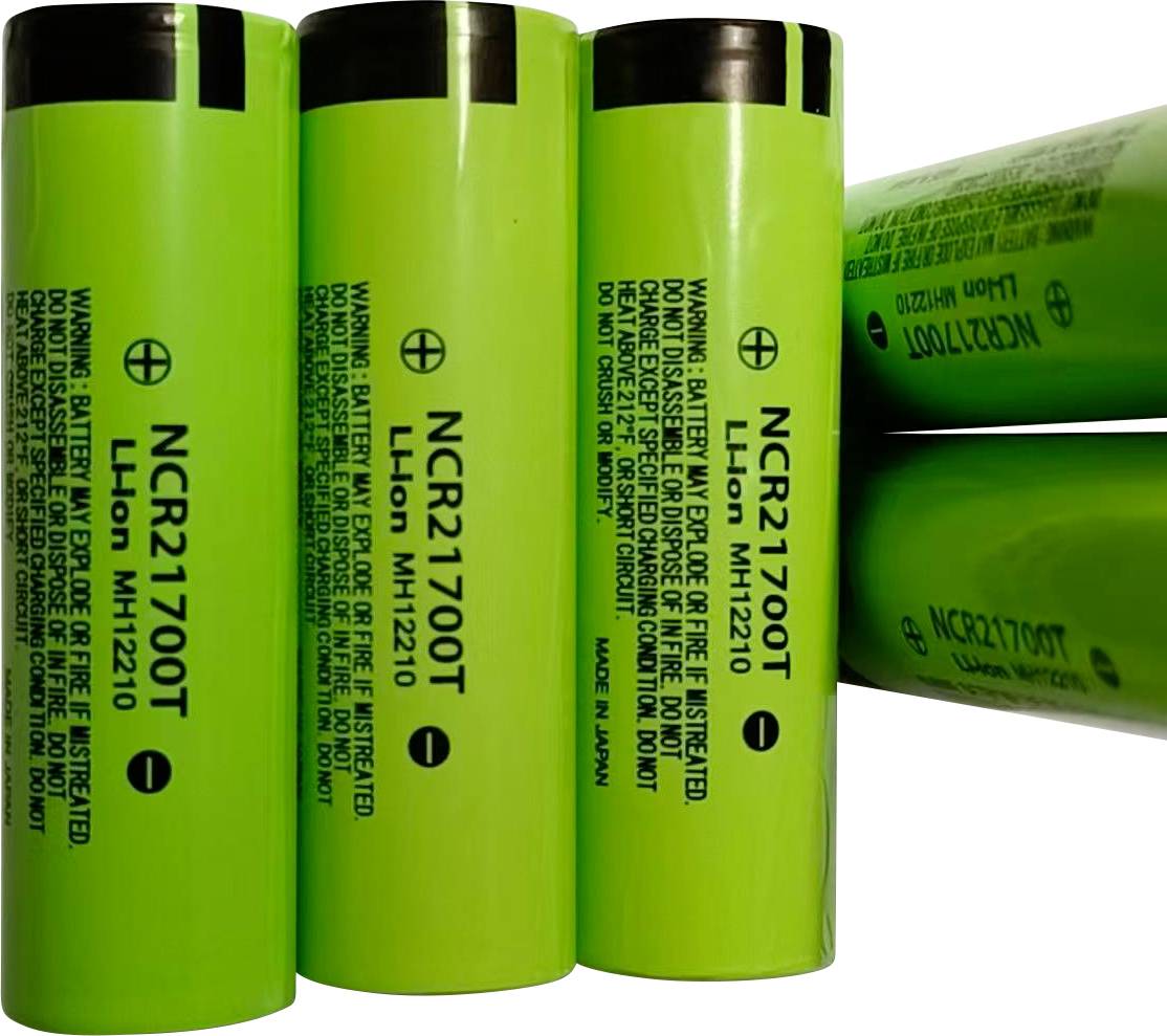 Vier grüne NCR21700T Lithium-Ionen-Batteriezellen, aufrecht dargestellt und auf ihrer Seite gestapelt, mit gedrucktem Warn- und Modelltext.