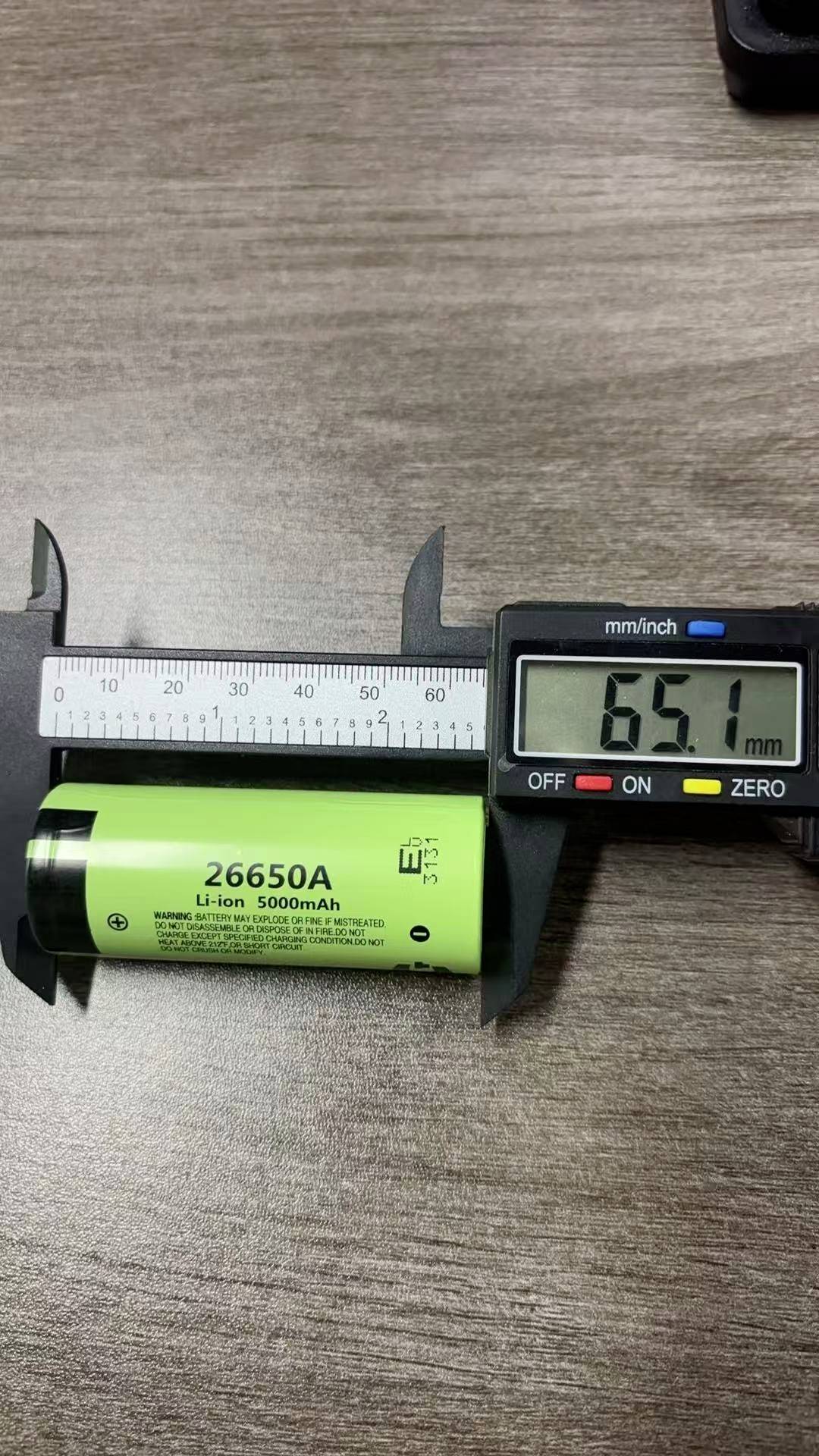 Digitale Schieblehre misst eine grüne 26650-Lithium-Ionen-Batterie und zeigt einen Durchmesser von 65,1 mm.