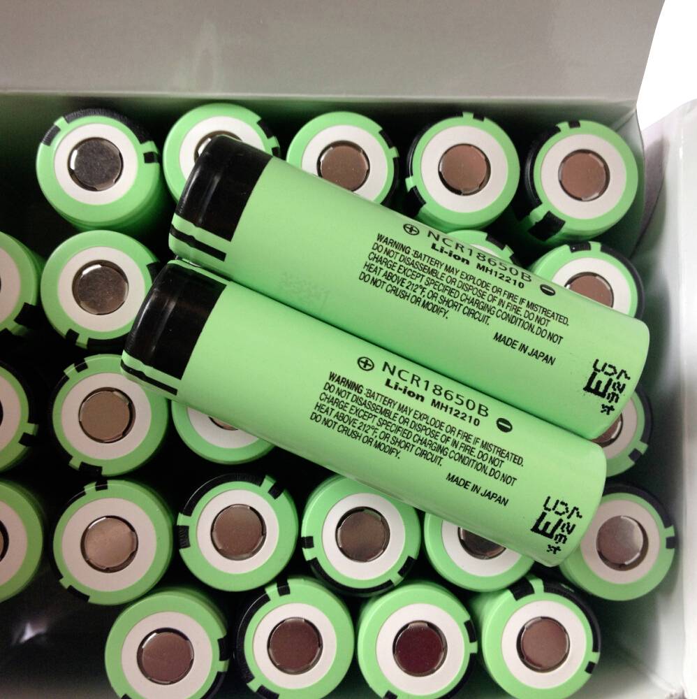 Schachtel grüner wiederaufladbarer Batterien mit zwei losen Batterien, die diagonal auf aufrecht stehenden Batterien in der Verpackung angeordnet sind.