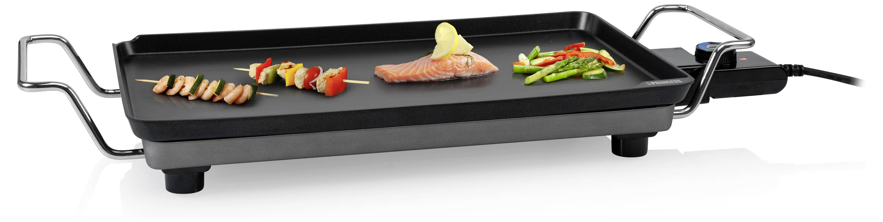 Elektrische Tischplatte mit drei Garzonen: geschnittenes Fleisch, Gemüse und ein Lachsfilet, das auf einer schwarzen antihaftbeschichteten Platte gegrillt wird.