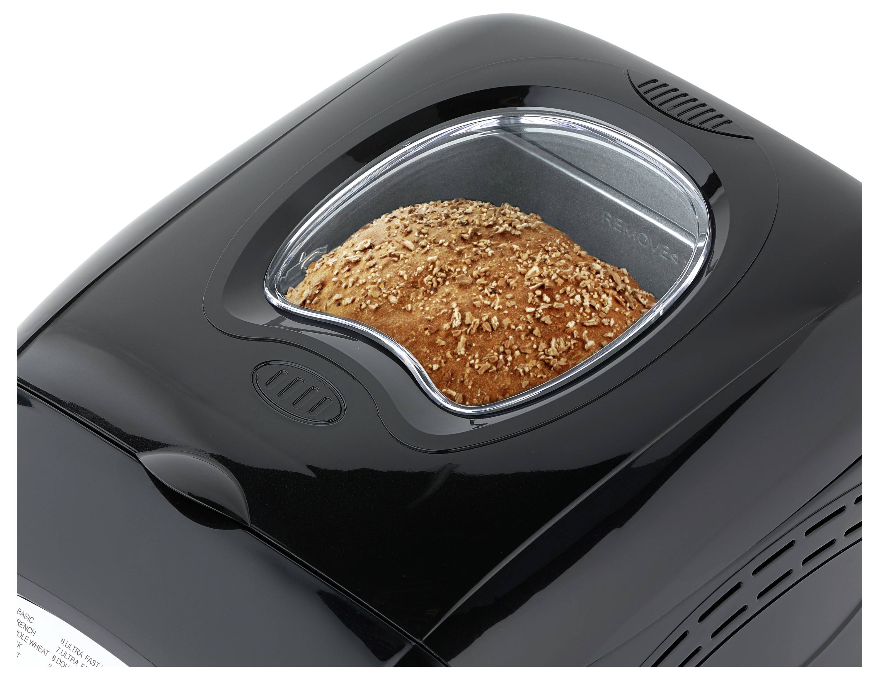 Schwarze Brotbackmaschine mit einem Laib Saatbrot, das durch ein durchsichtiges oberes Fenster im Inneren backt.