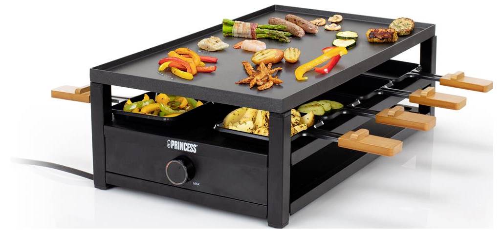 Elektrischer Tischgrill mit zwei Ablageebenen, auf dem verschiedene Fleischsorten, Gemüse und Meeresfrüchte auf Spießen und Tabletts zubereitet werden, vor weißem Hintergrund gezeigt.