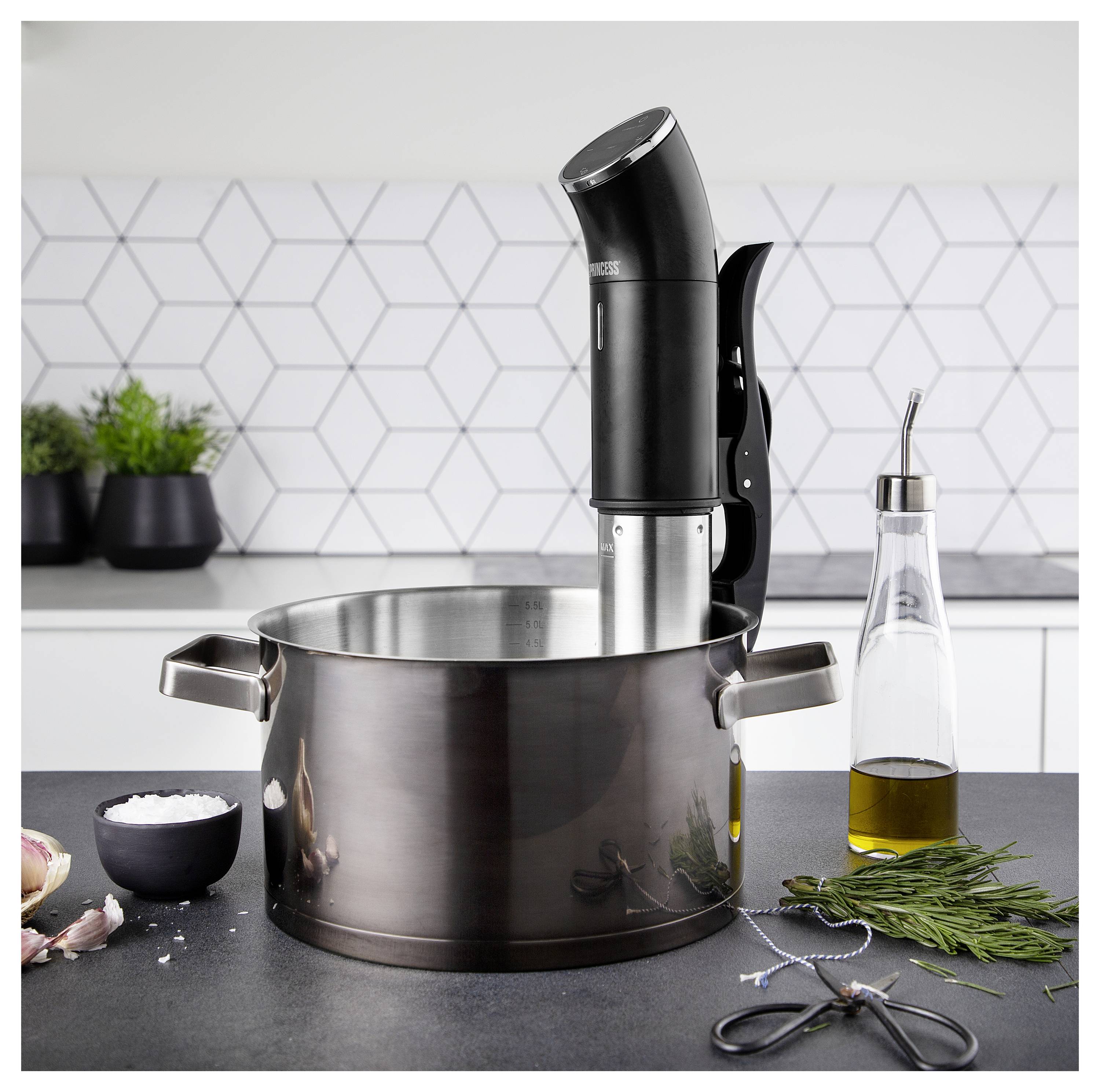 Küchenarbeitsplatte mit einem Edelstahltopf und einem Sous-Vide-Stabmixer, dazu Olivenöl, Kräuter, Schere und Salzschale.