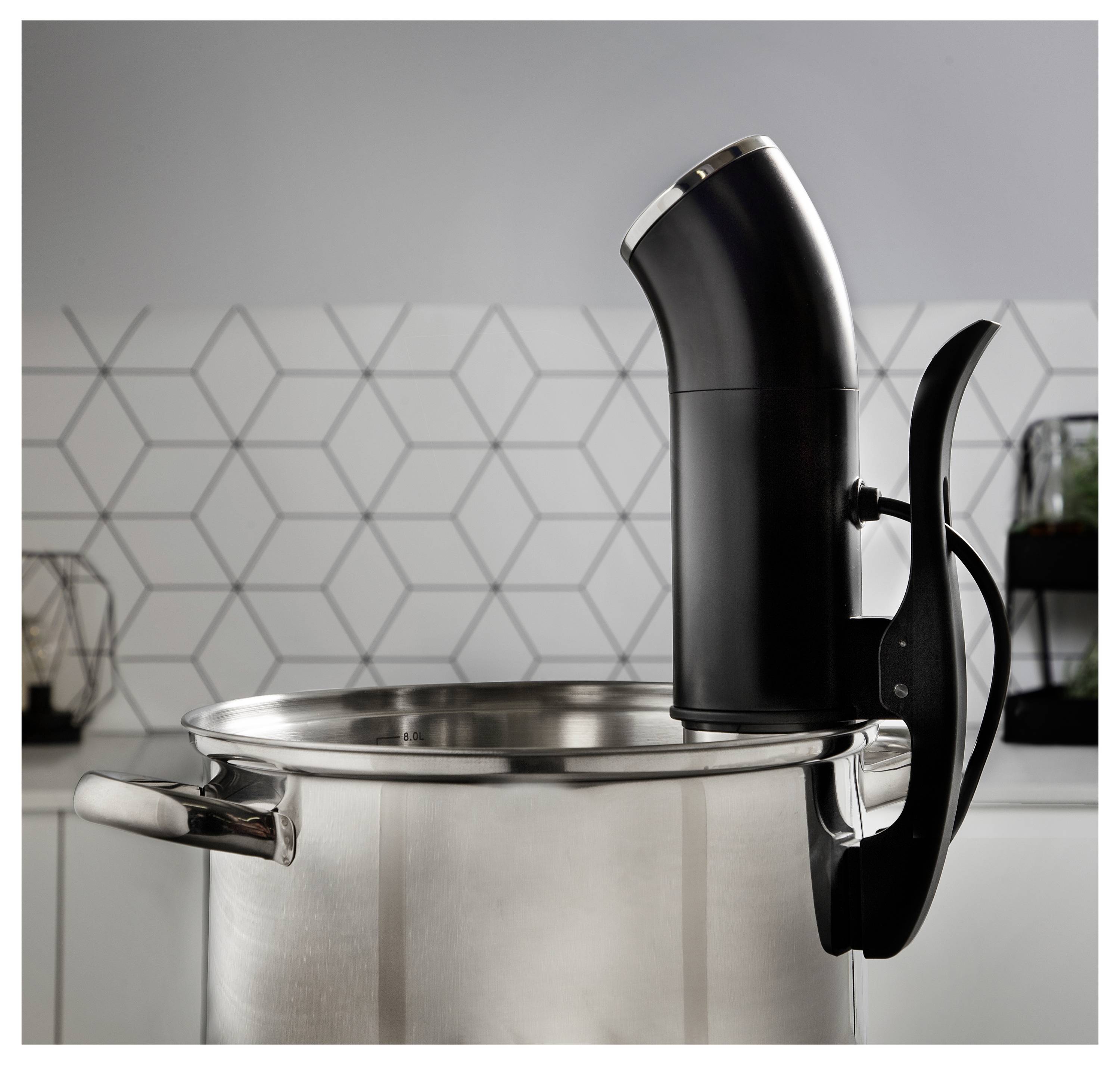 Schwarzer Immersionszirkulator, der an einem Edelstahltopf in einer Küche befestigt ist, bereit zum Sous-Vide-Garen.