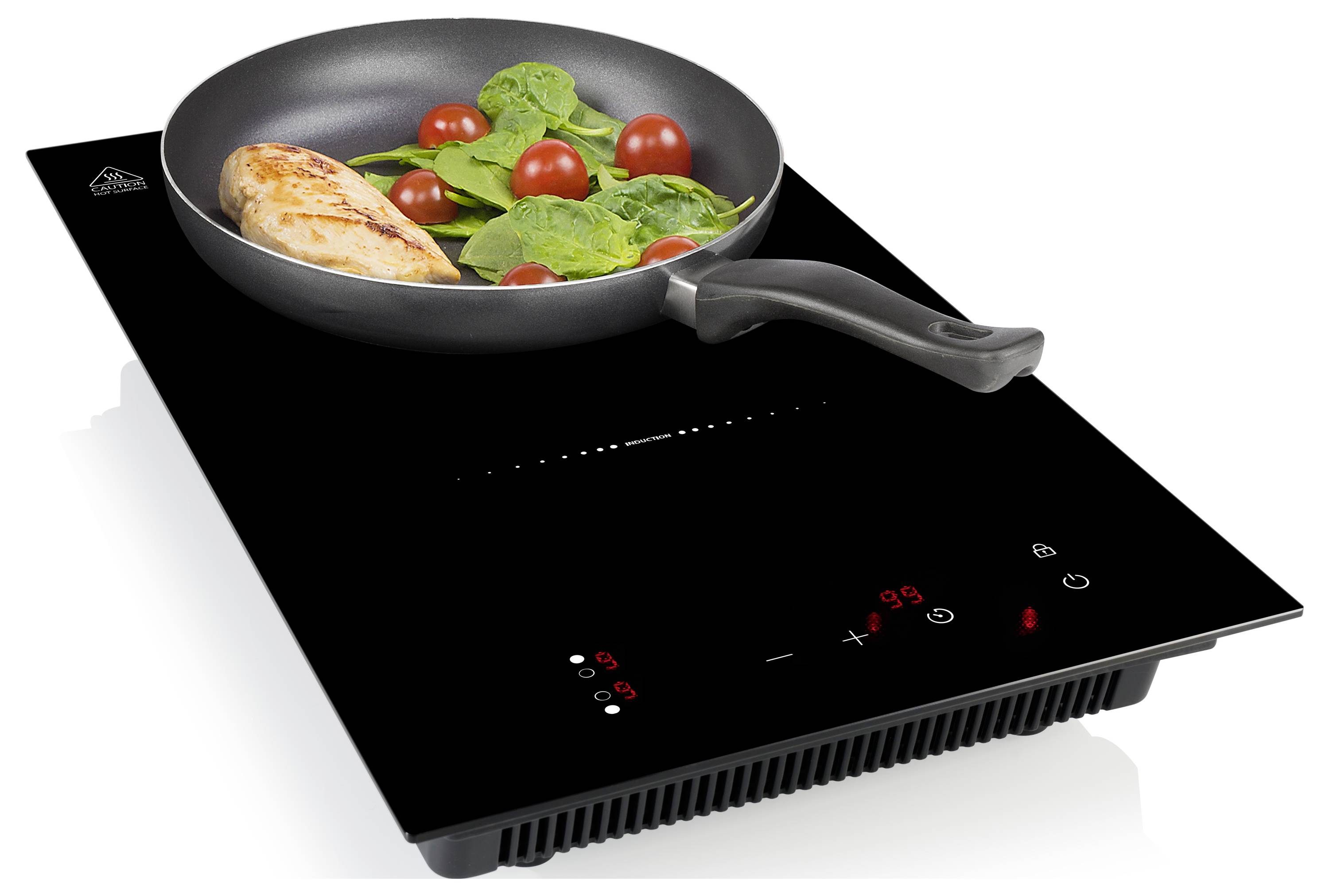 Schwarze Induktionskochplatte mit Touch-Bedienelementen, die eine Pfanne mit Huhn, Spinat und Kirschtomaten erhitzt.