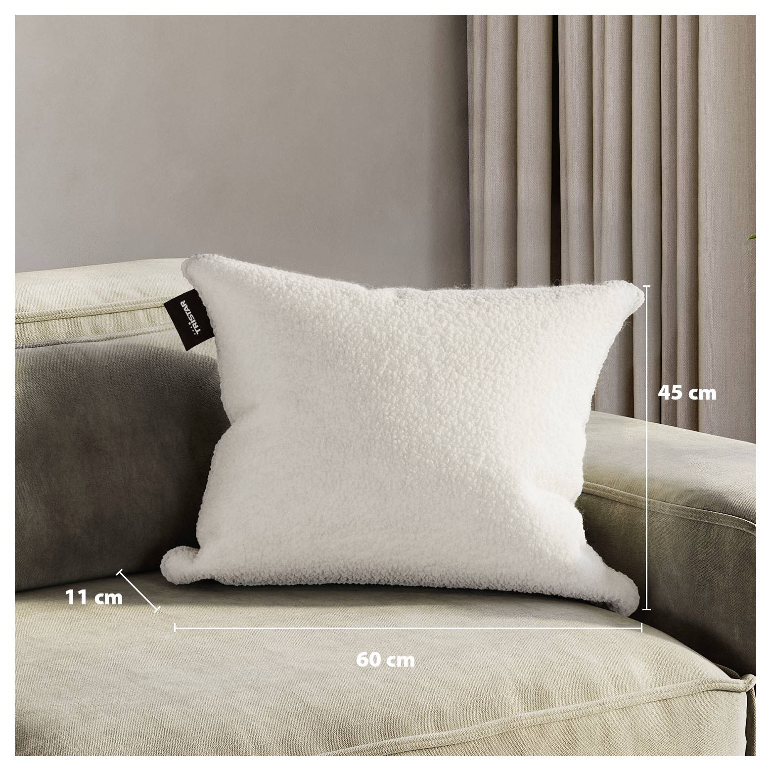 Weißes flauschiges rechteckiges Wurfkissen auf einem beigefarbenen Sofa, beschriftet mit 60 cm Breite und 45 cm Höhe, mit einer Tiefe von 11 cm.