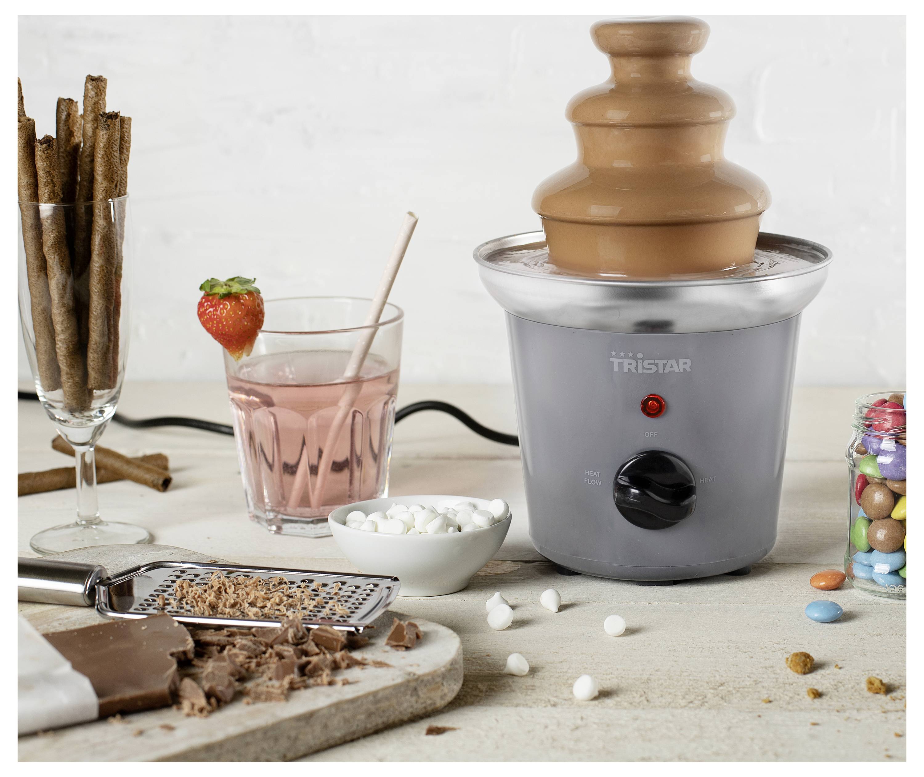 Schokoladen-Fondue-Brunnen mit geschmolzener Schokolade, die über Etagen fließt, umgeben von Erdbeeren, Marshmallows, Waffeln und Schokoladenstücken zum Dippen.