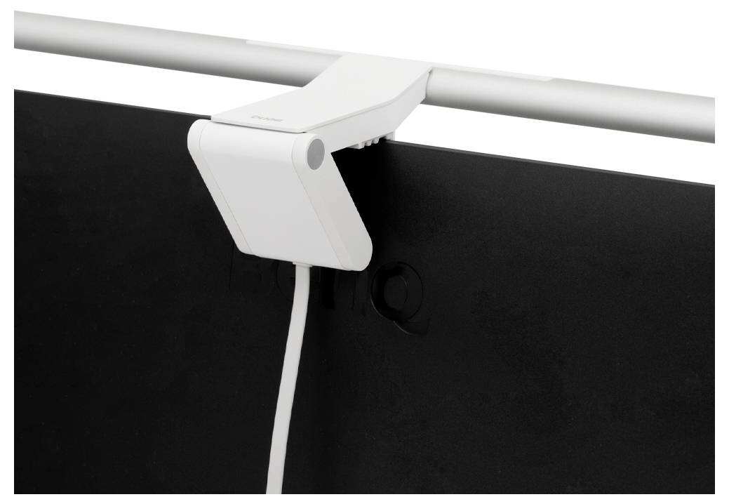 Ein weißes Klemmgerät, das an der oberen Kante eines dunklen Monitors befestigt ist, mit einem Kabel, das darunter hängt.