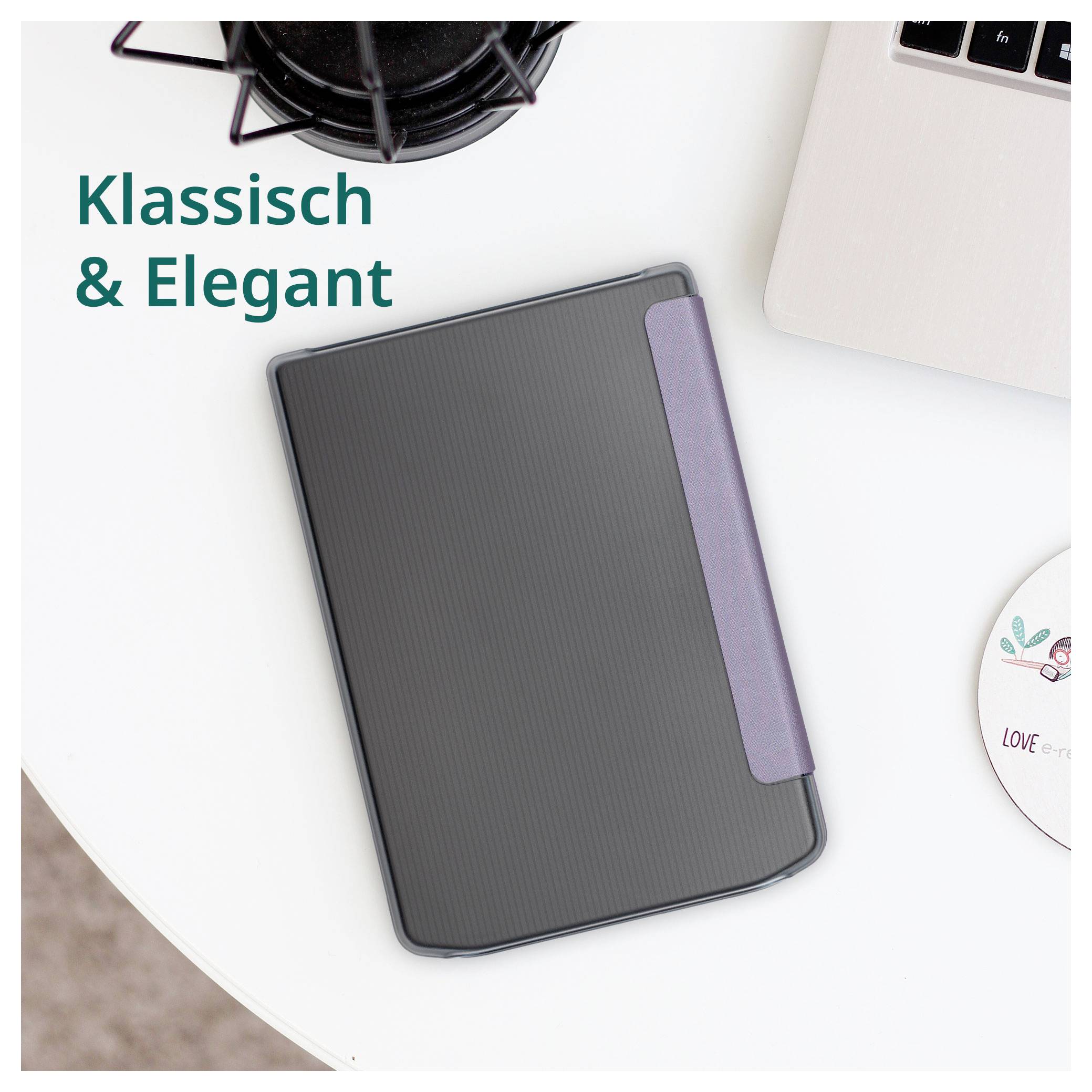 Ein schwarzes geripptes Notizbuch oder Planungsbuch mit einem violetten Gummiband, gezeigt auf einem weißen Schreibtisch neben einem Laptop und einer Kaffeetasse, mit dem Text „Klassisch & Elegant