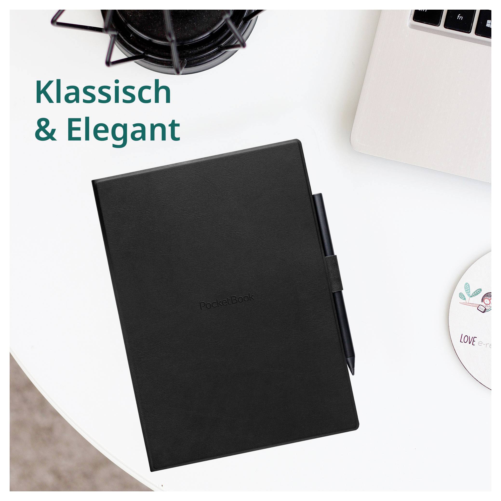 Schwarzes Notizbuch mit Stift auf einem weißen Schreibtisch, neben einem Laptop und einer Kaffeetasse, mit dem Text „Klassisch & Elegant