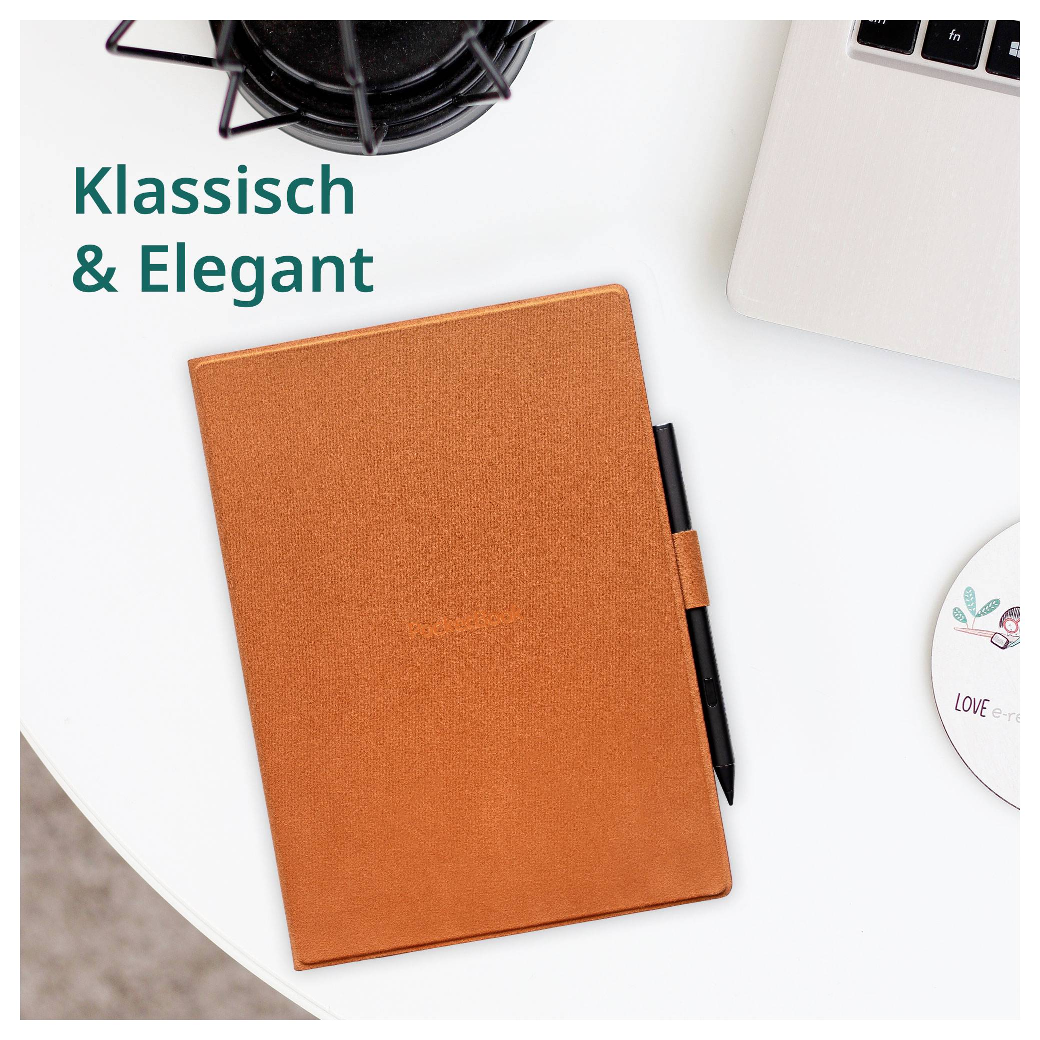 Orangenes Ledernotizuch mit Stift auf einem weißen Schreibtisch, beschriftet mit „Klassisch & Elegant