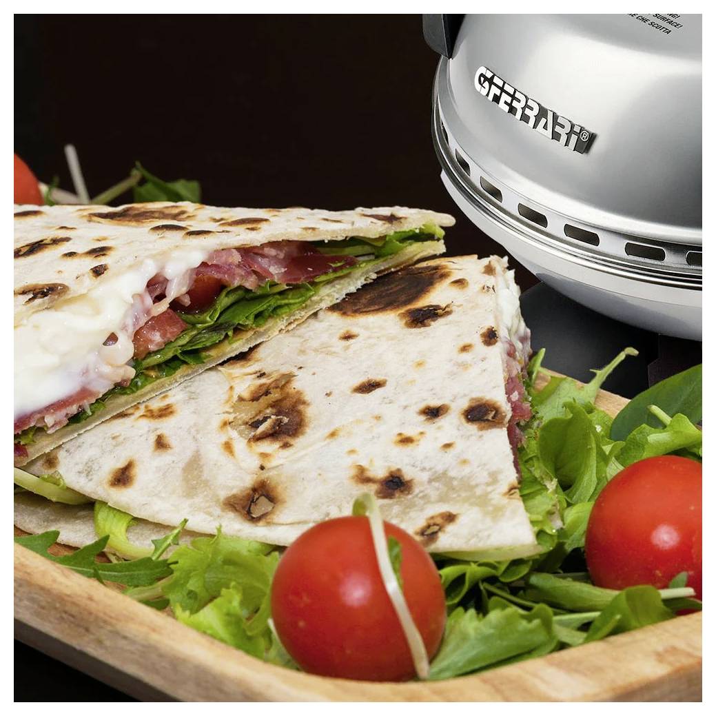 Gegrillte Quesadilla auf einem Holzbrett mit Grünzeug und Kirschtomaten neben einer Grillpresse aus Edelstahl.