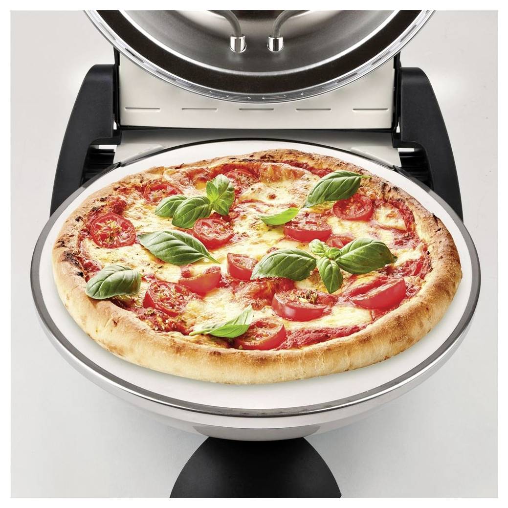 Ein Pizza backt in einem Pizzaofen auf der Arbeitsplatte, belegt mit Tomaten und Basilikum.
