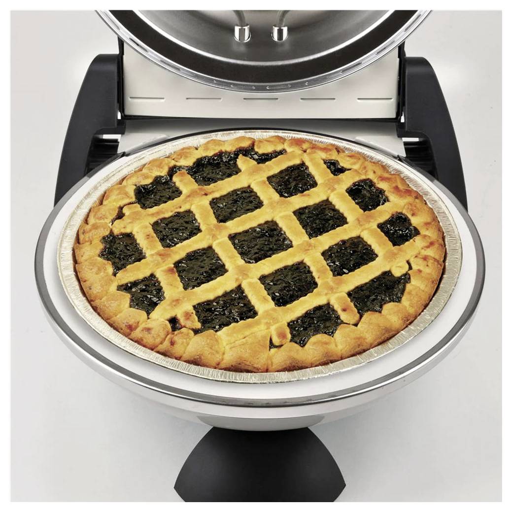 Ein gebackenes Gitteroberflächen-Kuchen in einer runden Metallform sitzt in einem offenen Arbeitsplatten-Ofen oder einer Wärmeschublade.
