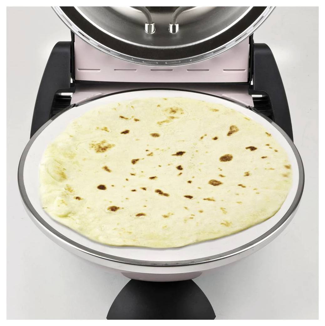 Eine flache Tortilla liegt auf einer runden elektrischen Grillplatte, mit offenem Deckel darüber, was darauf hindeutet, dass sie gerade gekocht oder gewärmt wird.