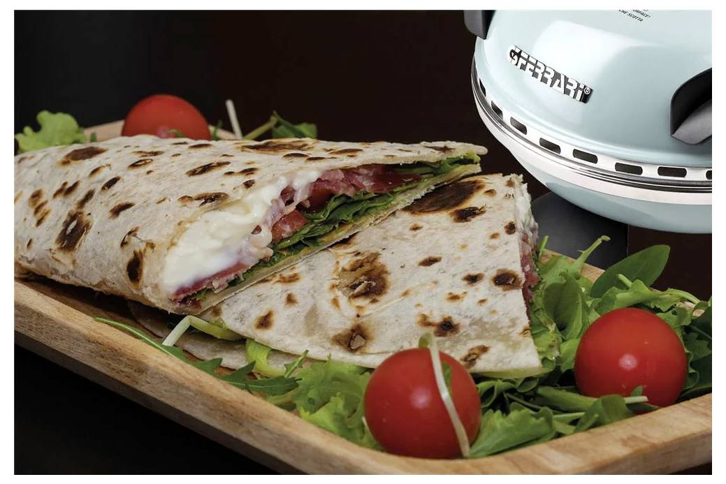 Gegrilltes Wrap-Sandwich auf einem Holzbrett mit Salat und Kirschtomaten, neben einer hellblauen Sandwichpresse.