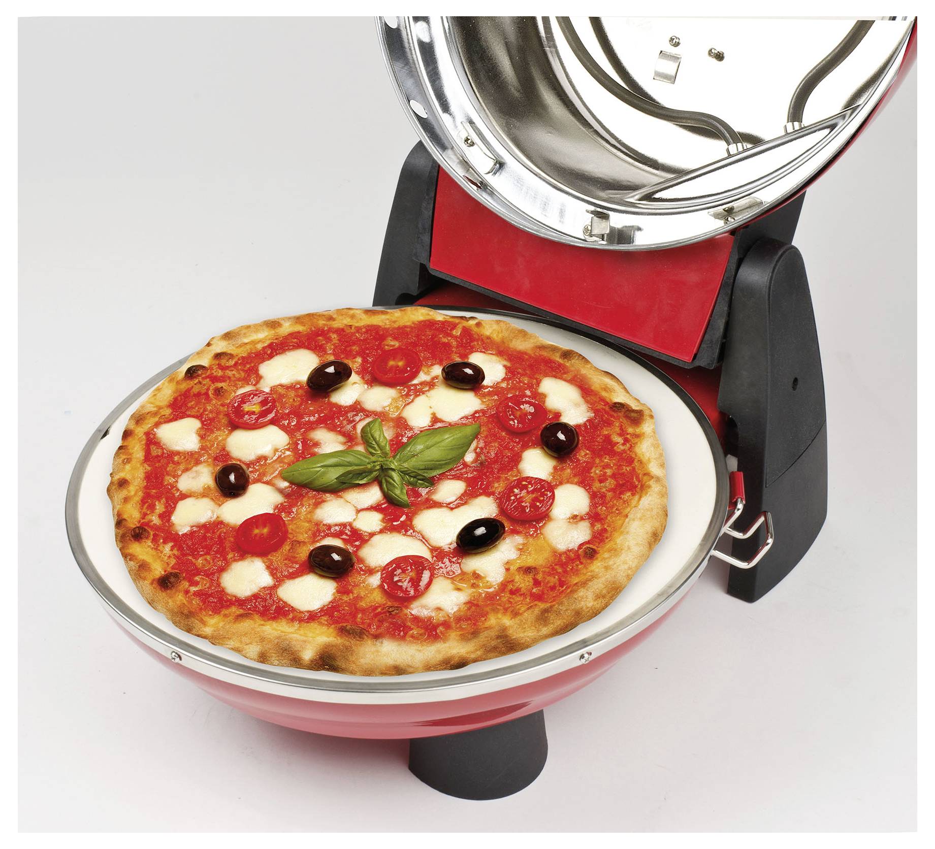 Pizza, die in einem Tischplatz-Pizzaofen mit offener Abdeckung zubereitet wird, belegt mit Basilikum, Oliven, Pepperoni und Käse auf weißem Hintergrund.