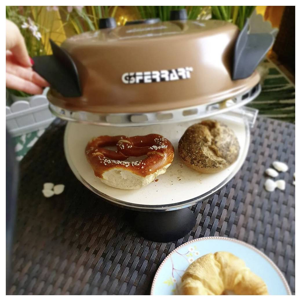 Ein Tischplattenlebensmittelwärmer, der zwei Gebäckstücke zeigt, darunter eine glasierte brezelförmige Rolle und ein gezuckertes Brötchen, mit einem teilweise sichtbaren Croissant darunter.