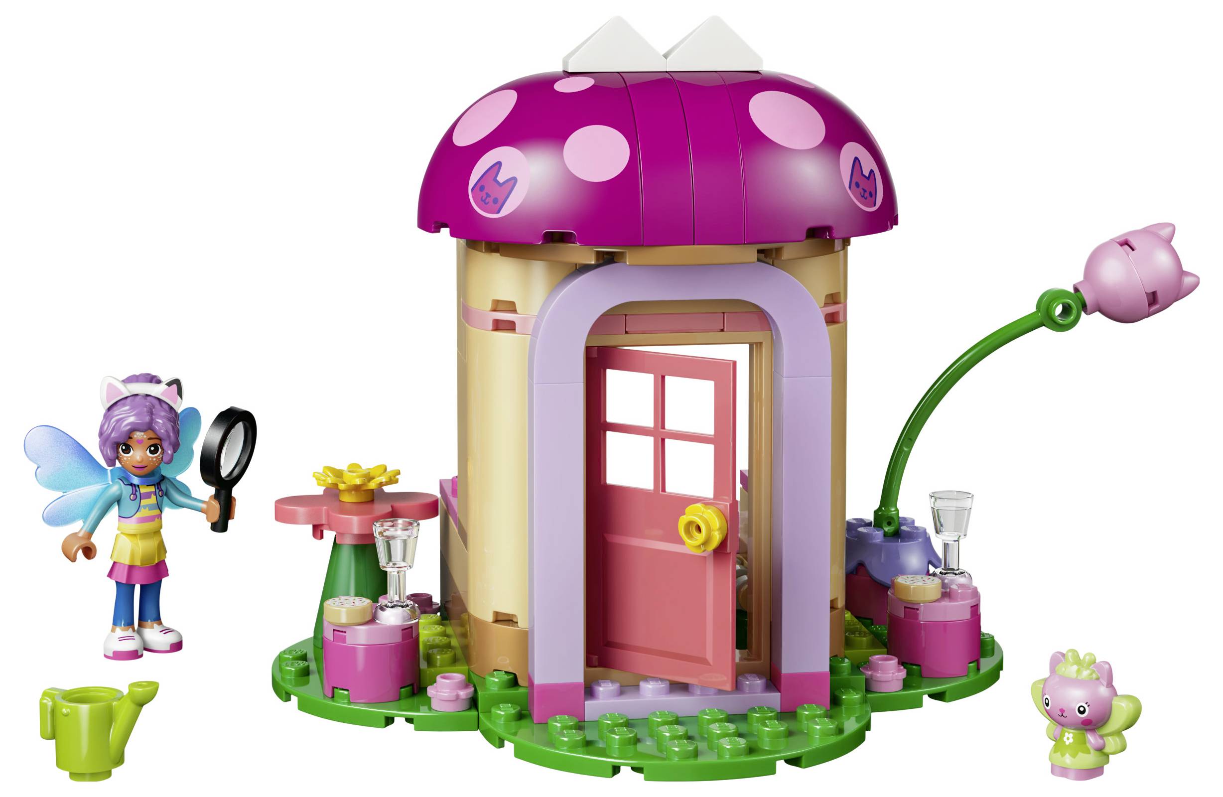 Spielzeug-Feenhaus-Set mit einem rosa pilzförmigen Dach, offener Tür und kleinen Feenfiguren sowie Zubehör ringsum.