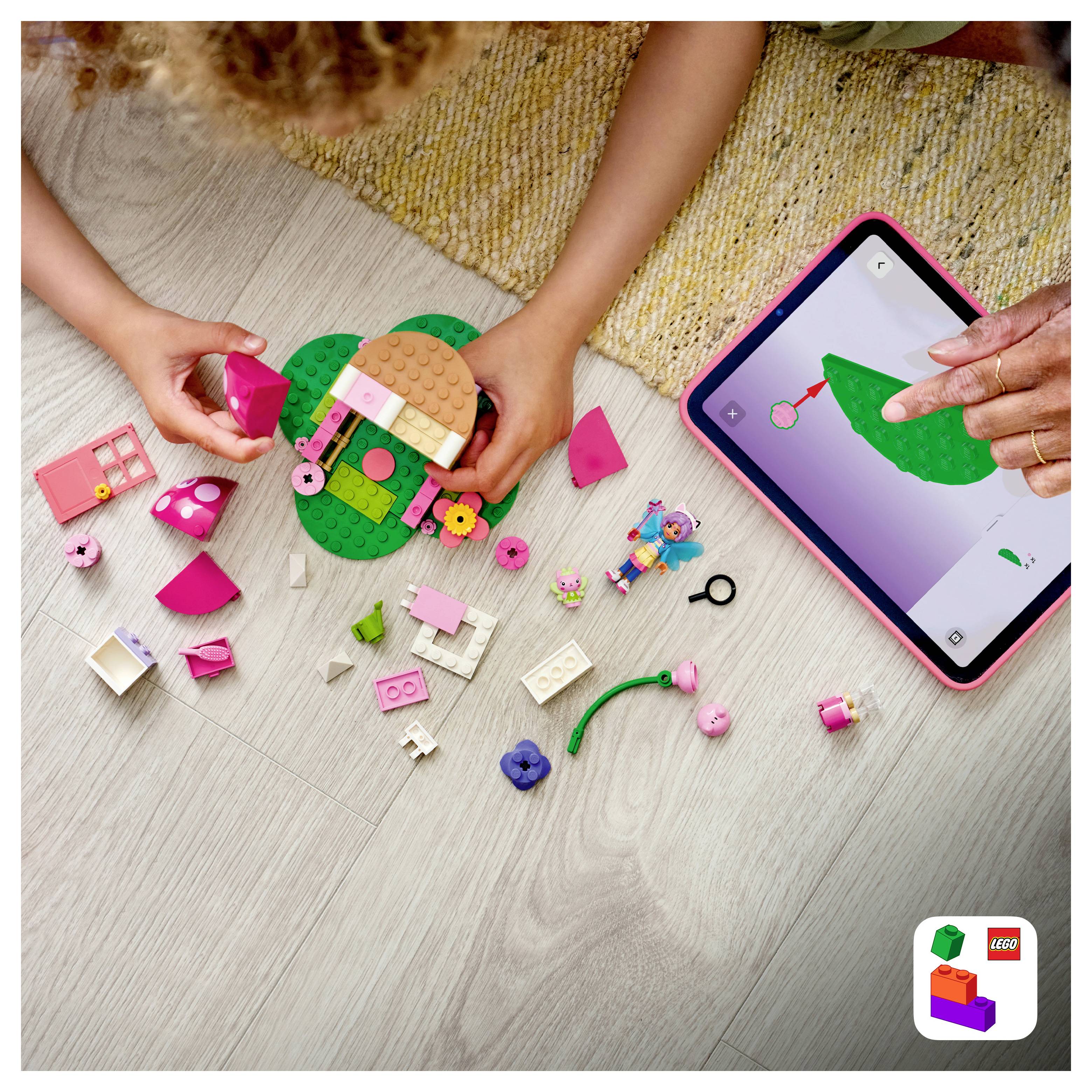 Kinder bauen ein kleines LEGO-Haus auf einer grünen Grundplatte, während ein Kind Anweisungen auf einem Tablet mit dem Design befolgt.