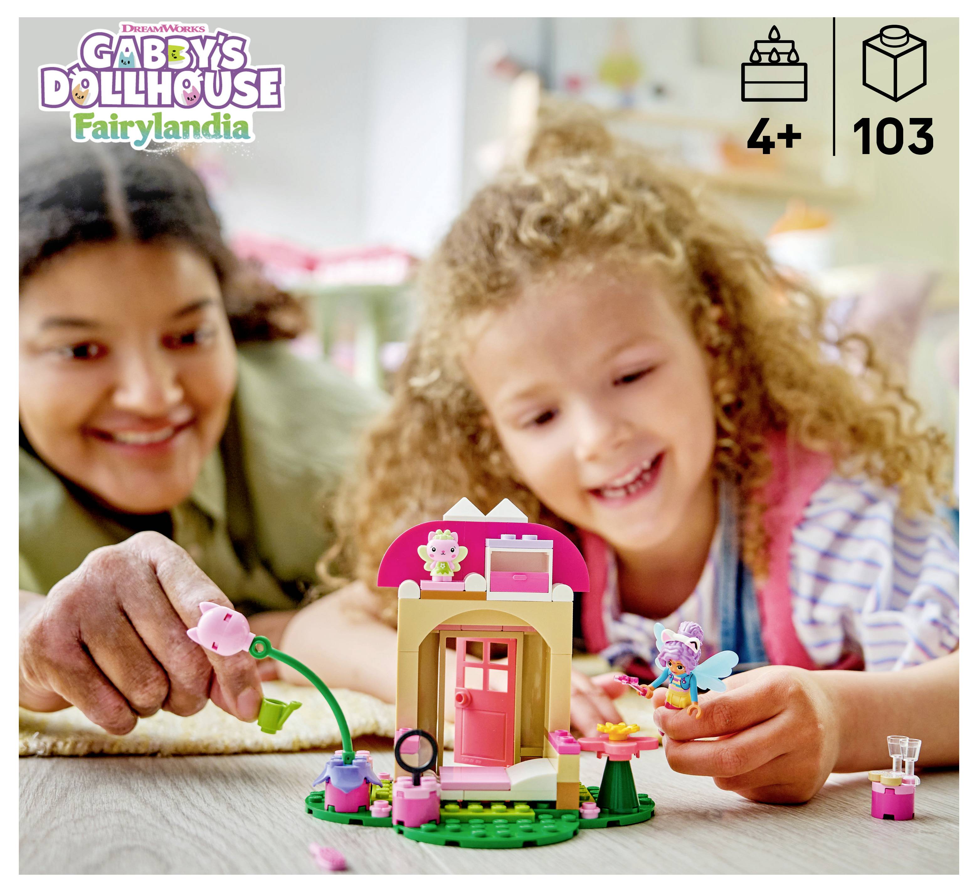 Kind und Erwachsener lächeln beim Spielen mit einem LEGO Gabby's Dollhouse Fairylandia Set, das das kleine Feenhaus und Minifiguren zeigt; ab 4 Jahren, 103 Teile.