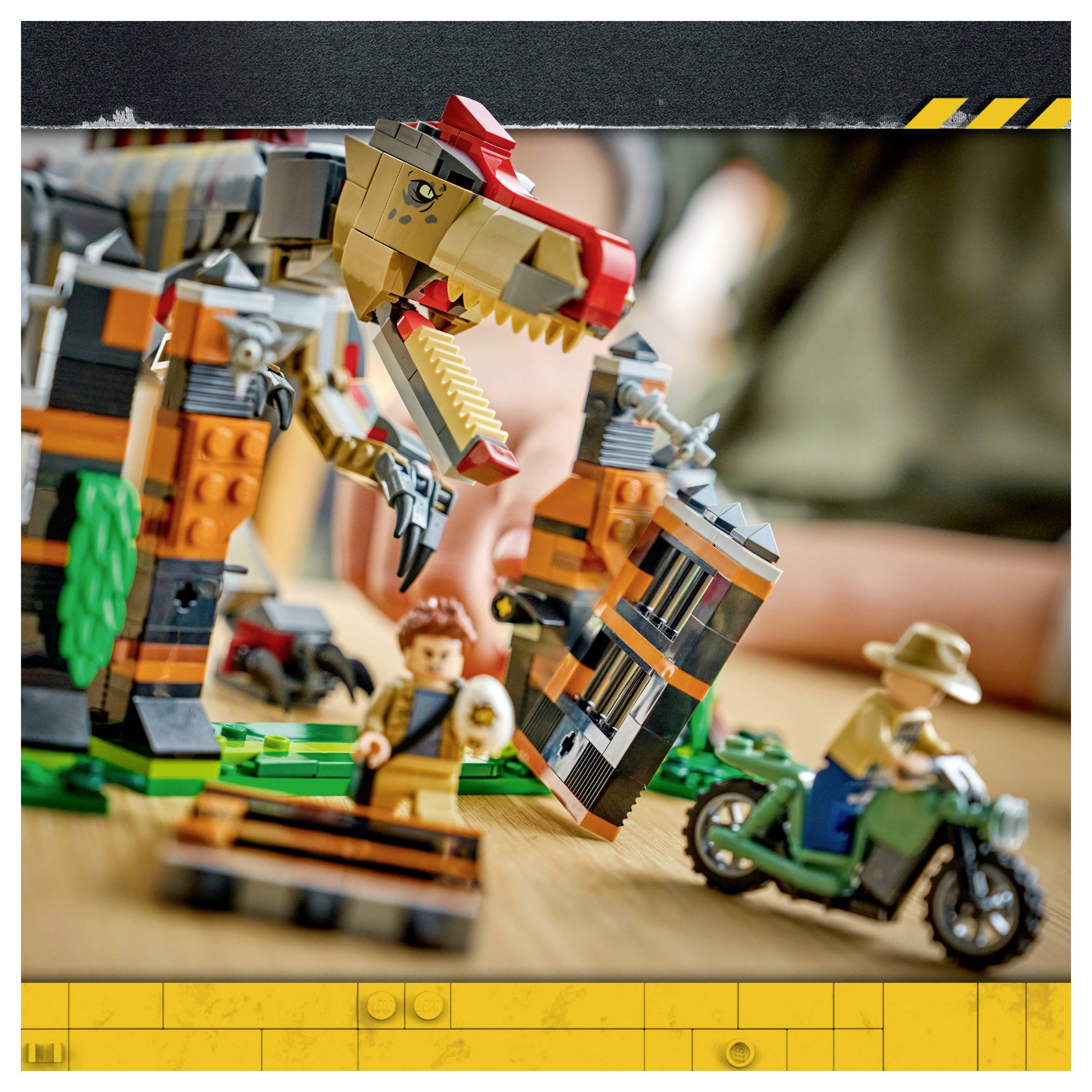 LEGO-Dinosaurierszenario mit einem riesigen T-Rex, Minifiguren und einem Motorradrennfahrer auf einer Tischplatte-Set.