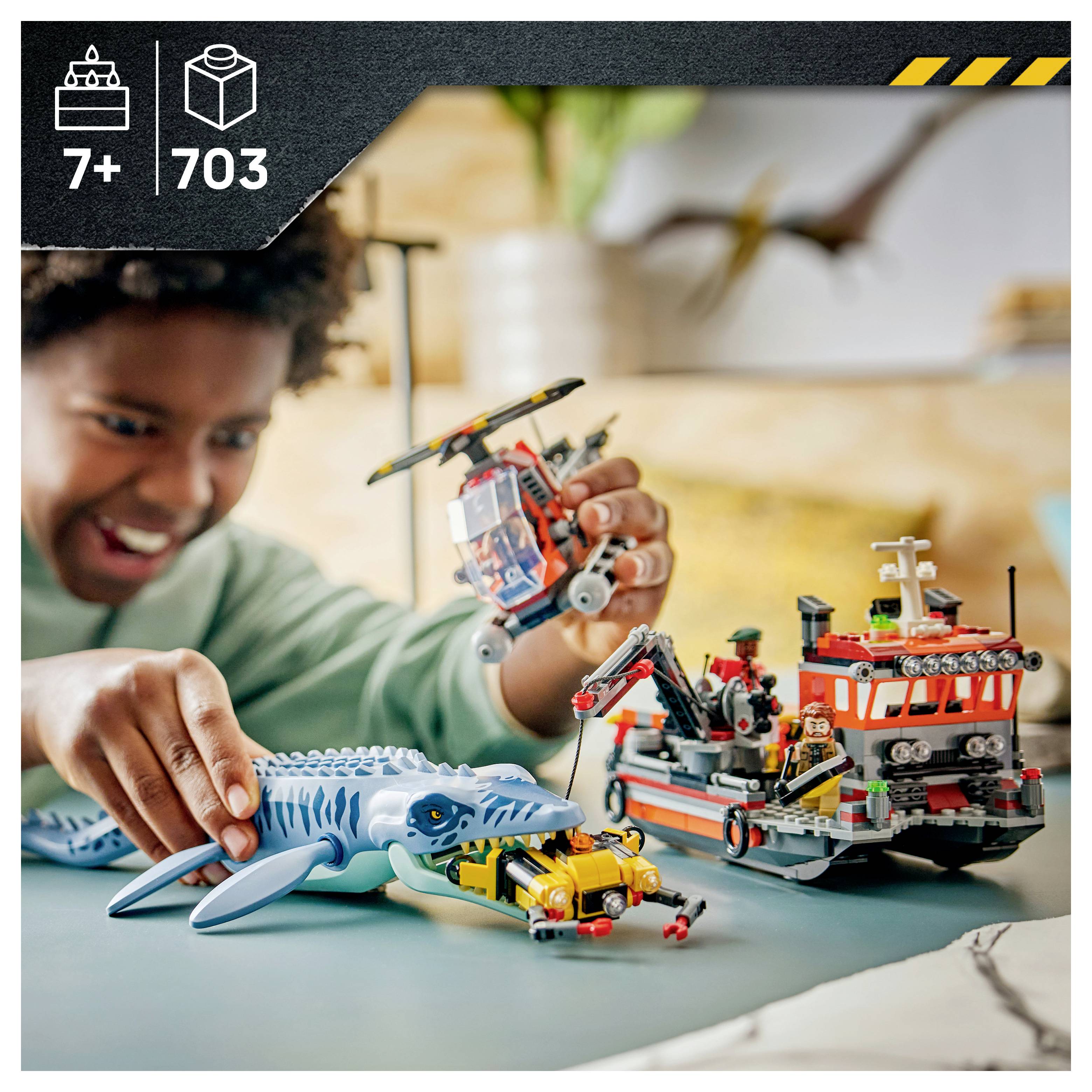 Kind spielt mit LEGO-ähnlichen Spielzeugen zur Meeresrettung, einschließlich eines Hais, eines Hubschraubers und eines Rettungsboot-Sets mit der Kennzeichnung 7+ und 703 Teilen.