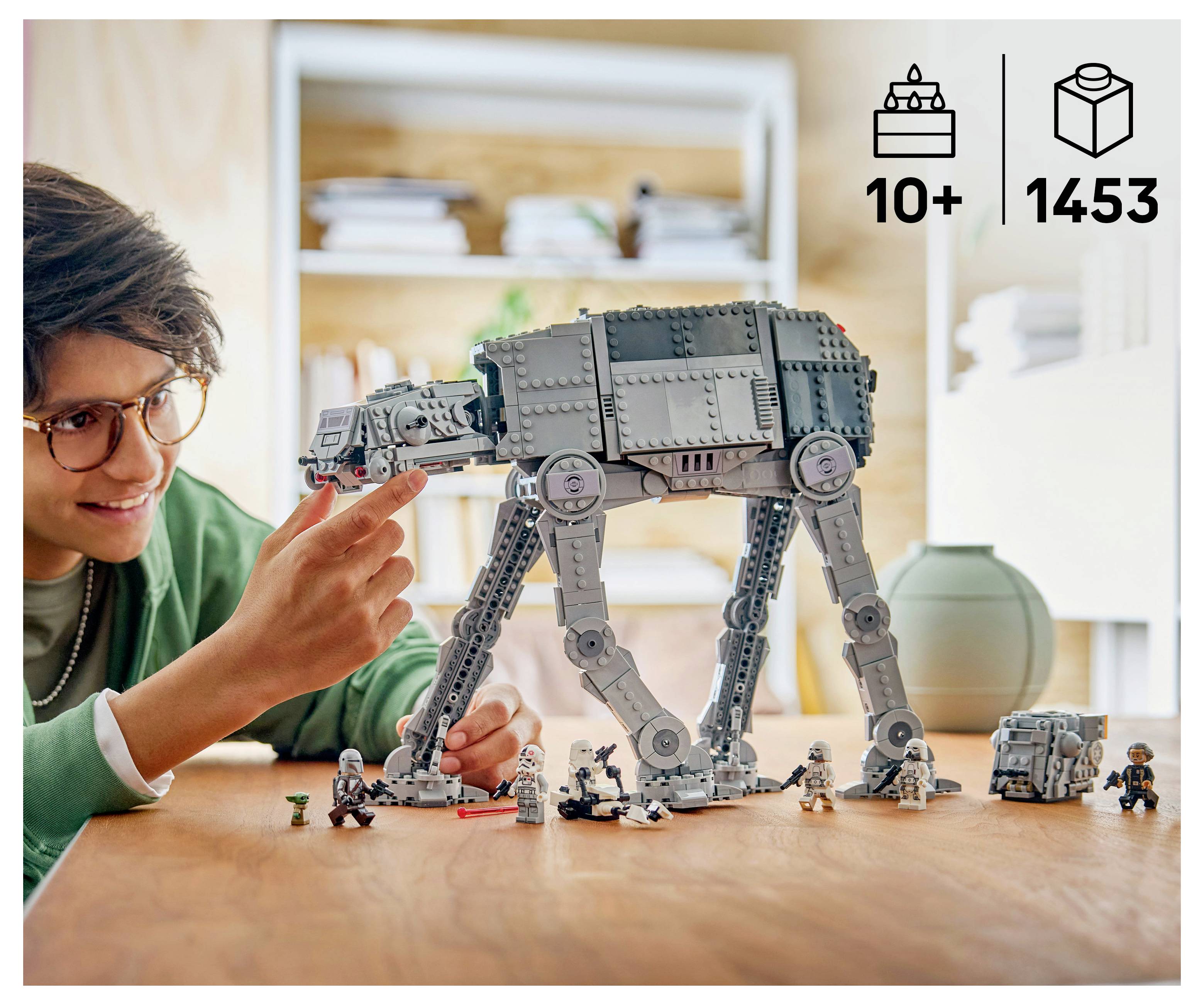 Eine Person baut einen LEGO AT-AT-Wanderer auf einem Tisch zusammen, mit den Produktsymbolen „10+
